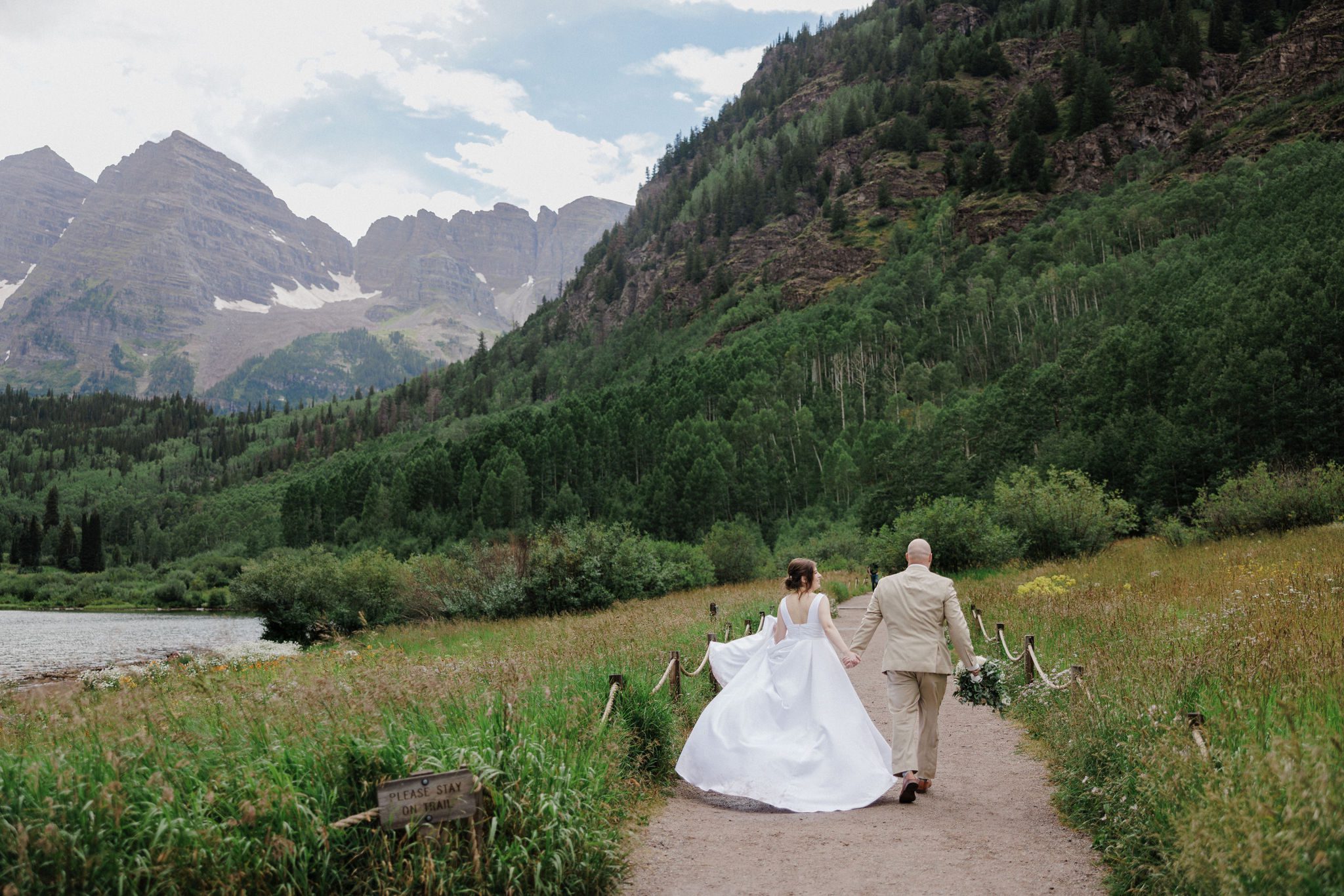 bride and groom walk down trail to get married at colorado fall wedding venue- maroon bells