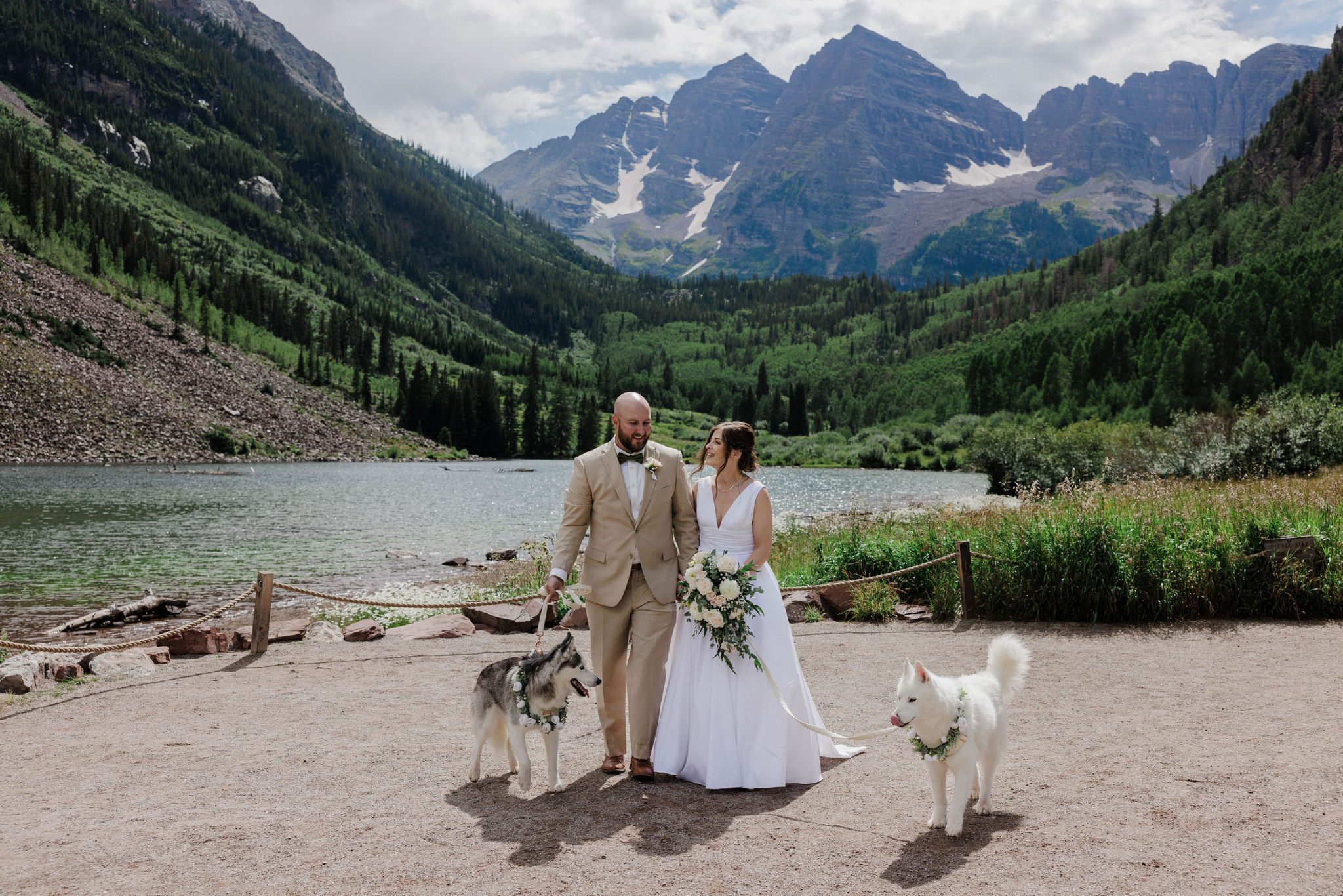 bride, groom, and dogs walk around maroon bells lake during colorado mountain wedding