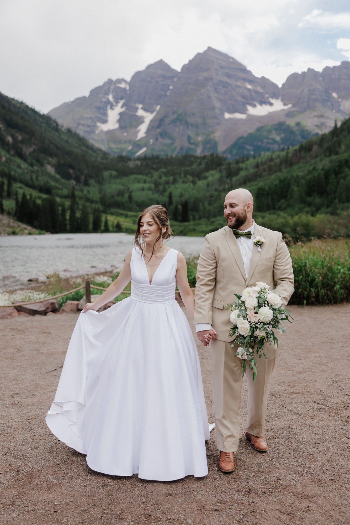 bride and groom walk around maroon bells during their colorado mountain lake wedding