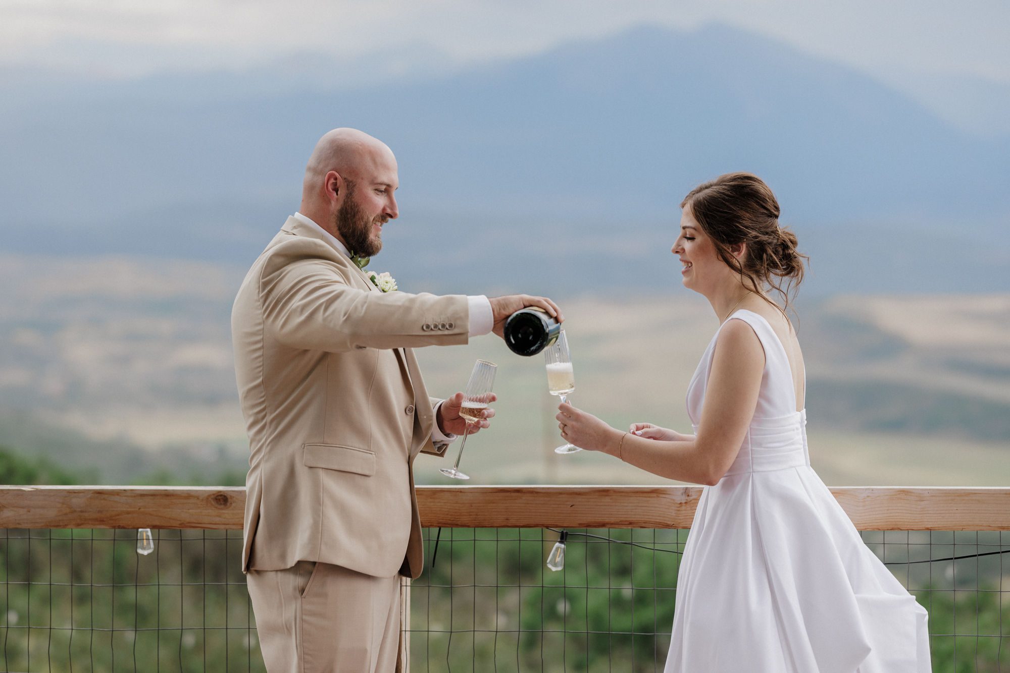 bride and groom pour champagne on deck of colorado airbnb micro wedding venue