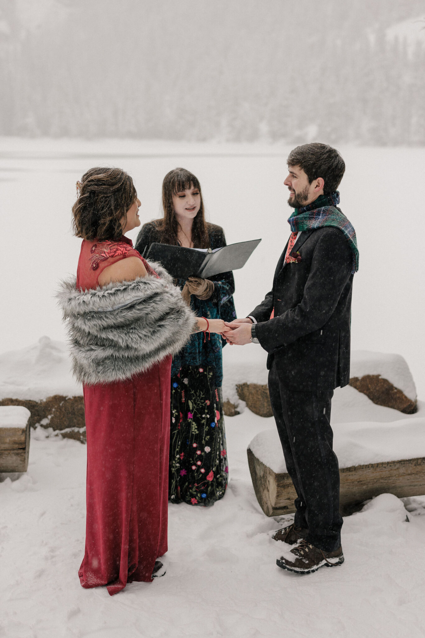 bride and groom hold hands during colorado mountain lake wedding at RMNP in the winter