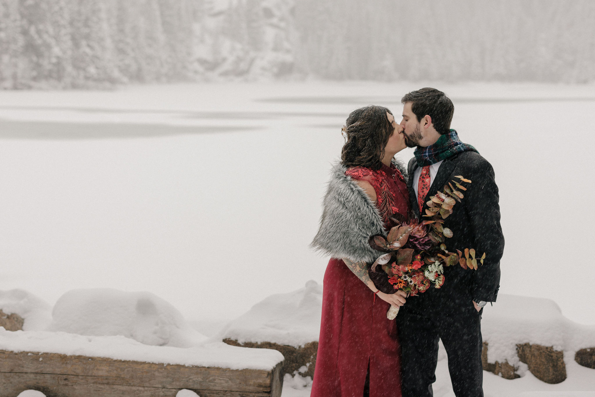 bride and groom kiss in front of bear lake at RMNP during their winter mountain lake elopement