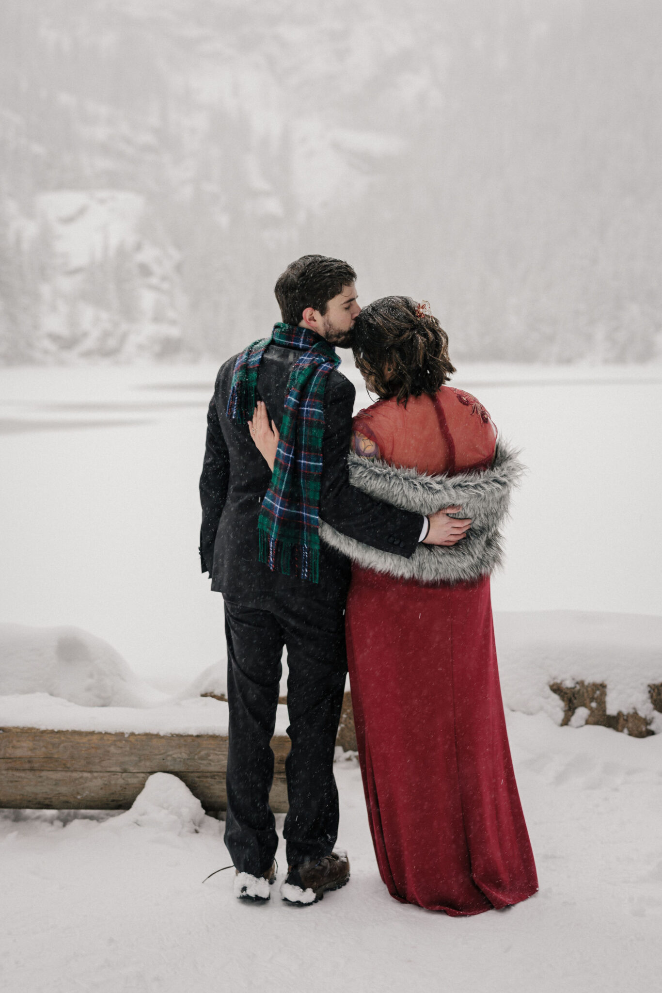 groom kisses brides head during wedding photos at their colorado mountain lake elopement at bear lake