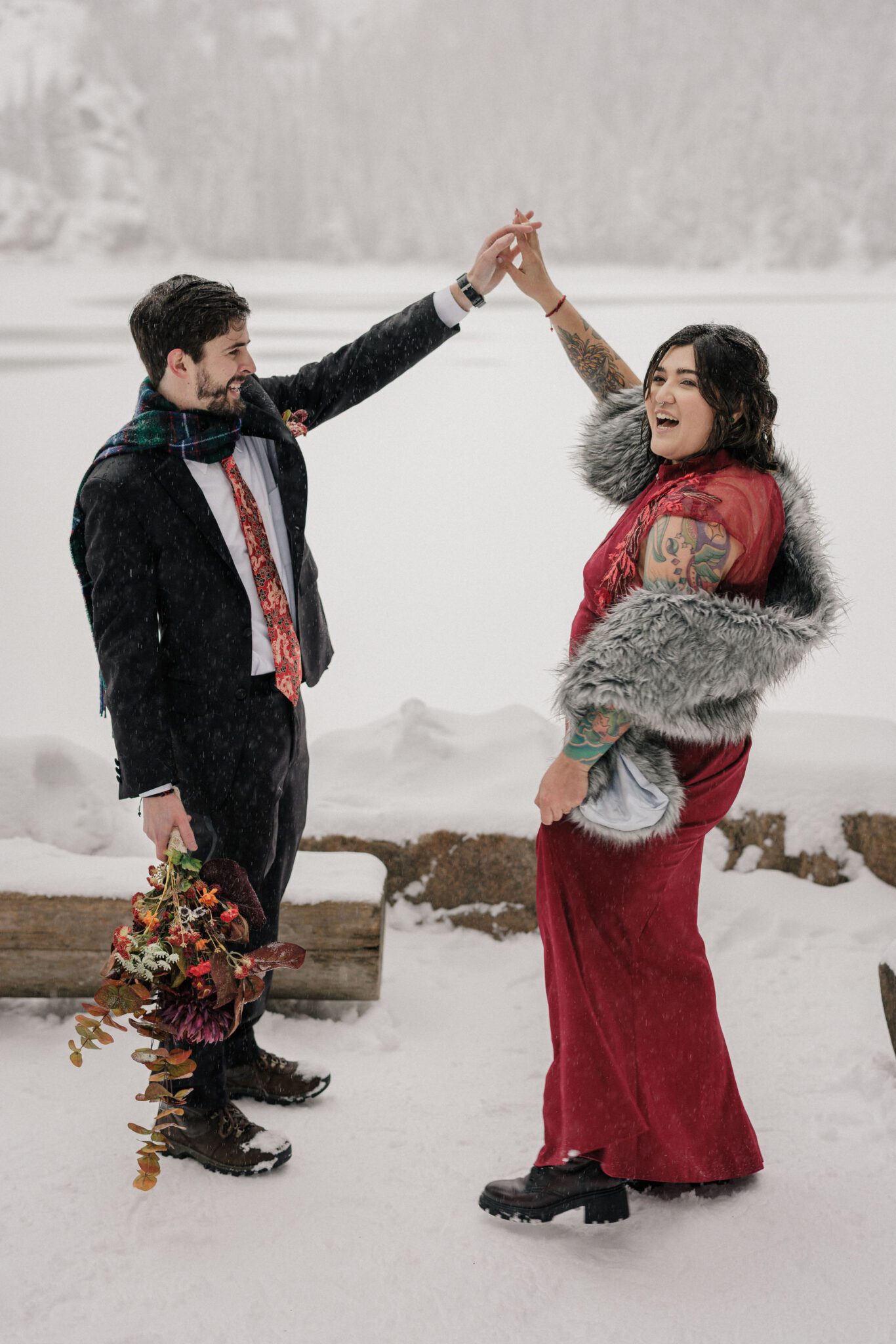 bride and groom pose for photographer during their mountain lake wedding in RMNP