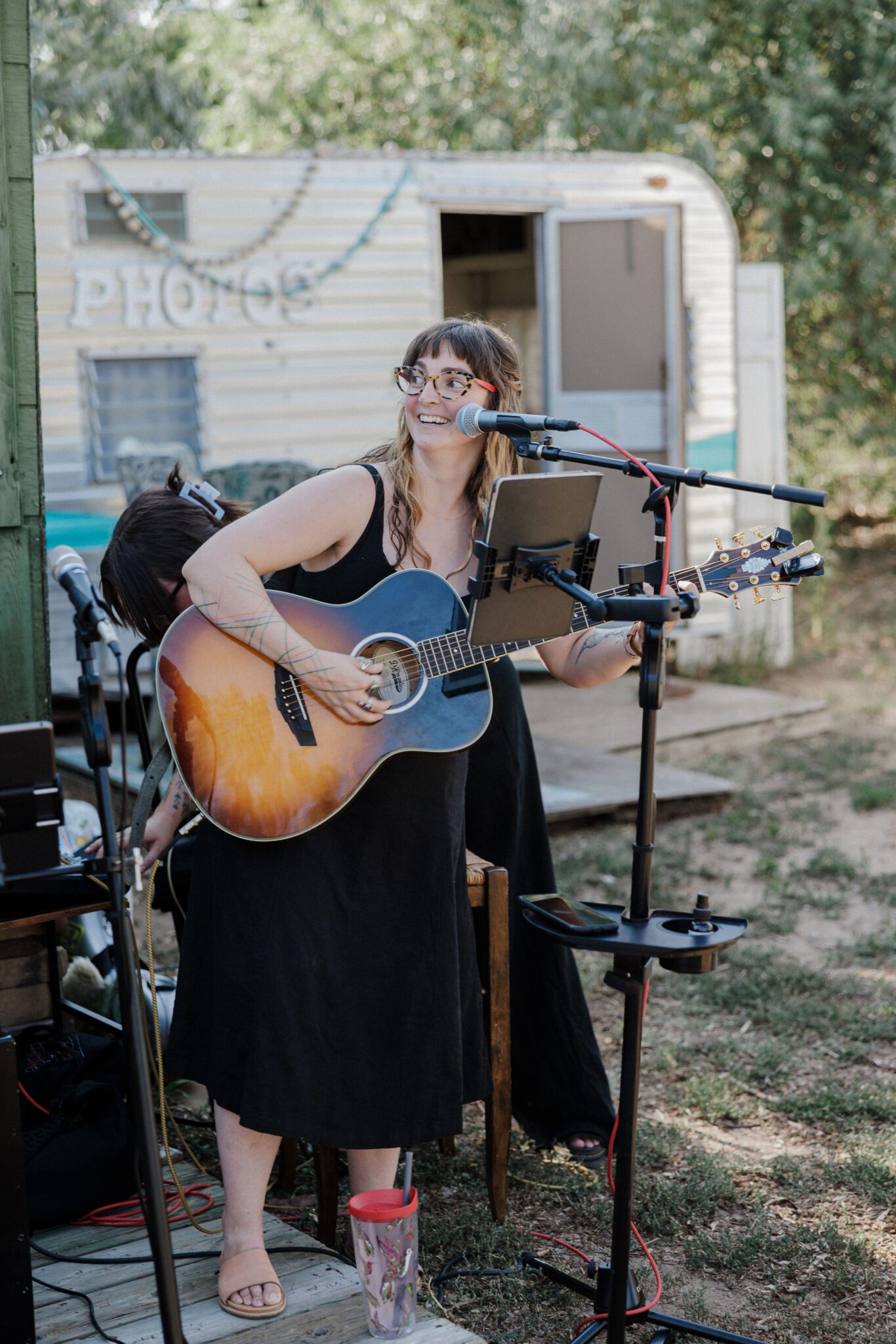 woman plays guitar during backyard wedding reception