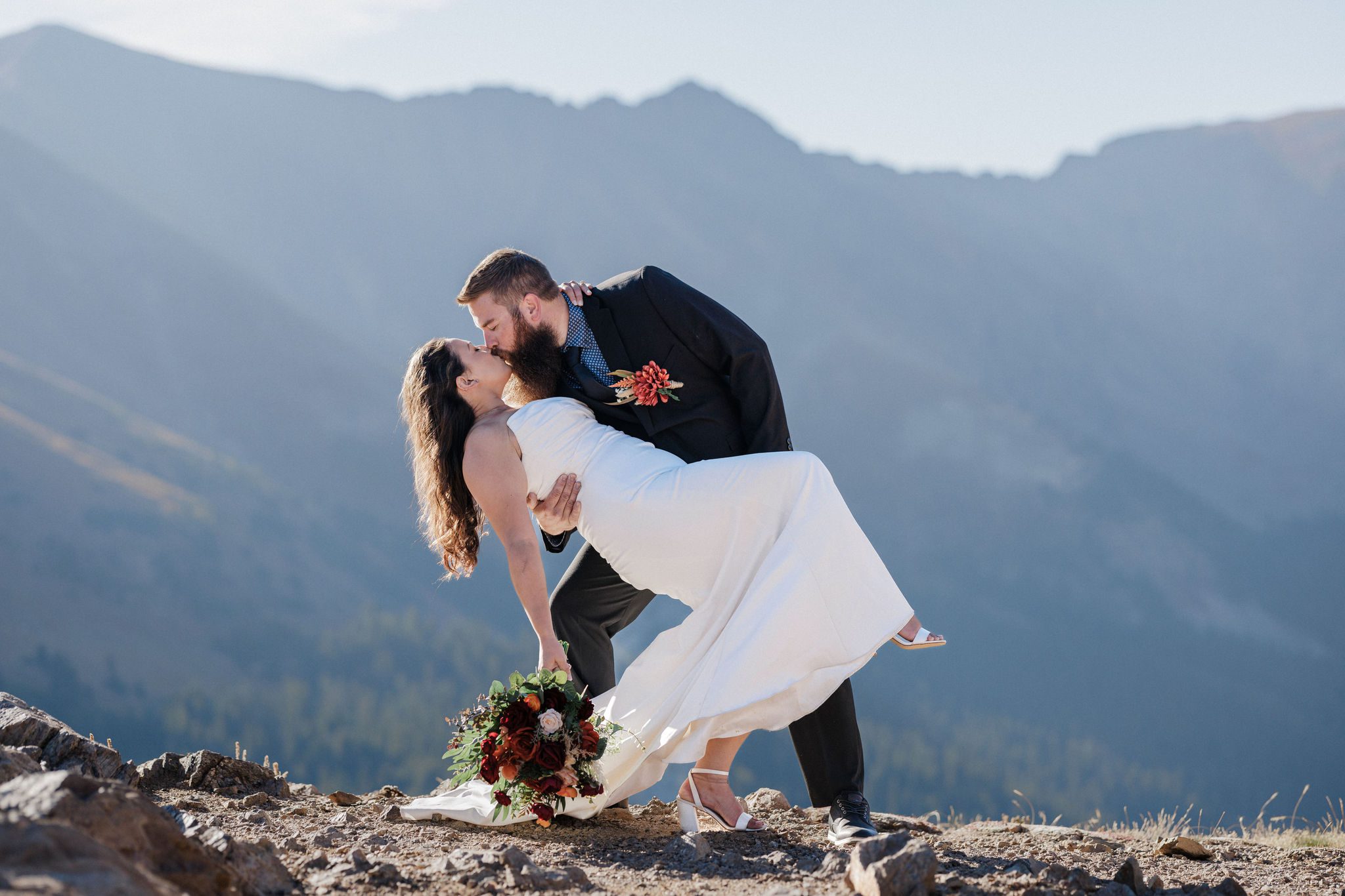 grooms dips and kisses bride in front of the montains while embracing the new meaning of 'elope' 