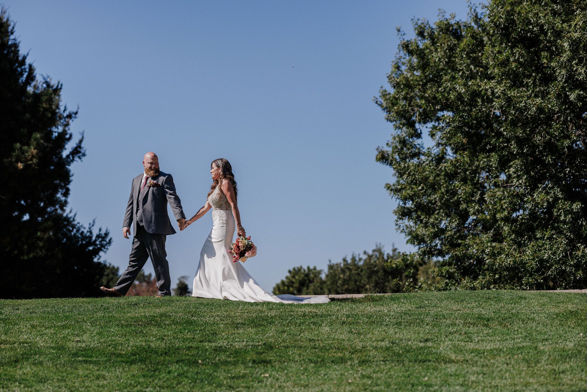 bride and groom hold hands and walk around a popular spot for colorado engagement photos