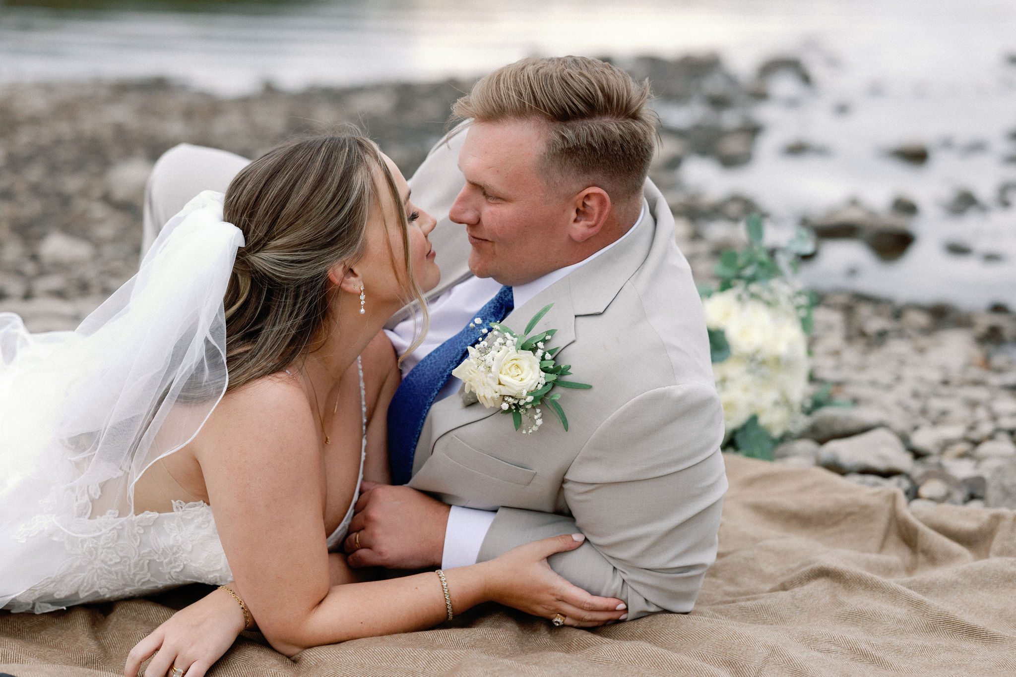 bride and groom lay down on blanket at the edge of lake dillon
