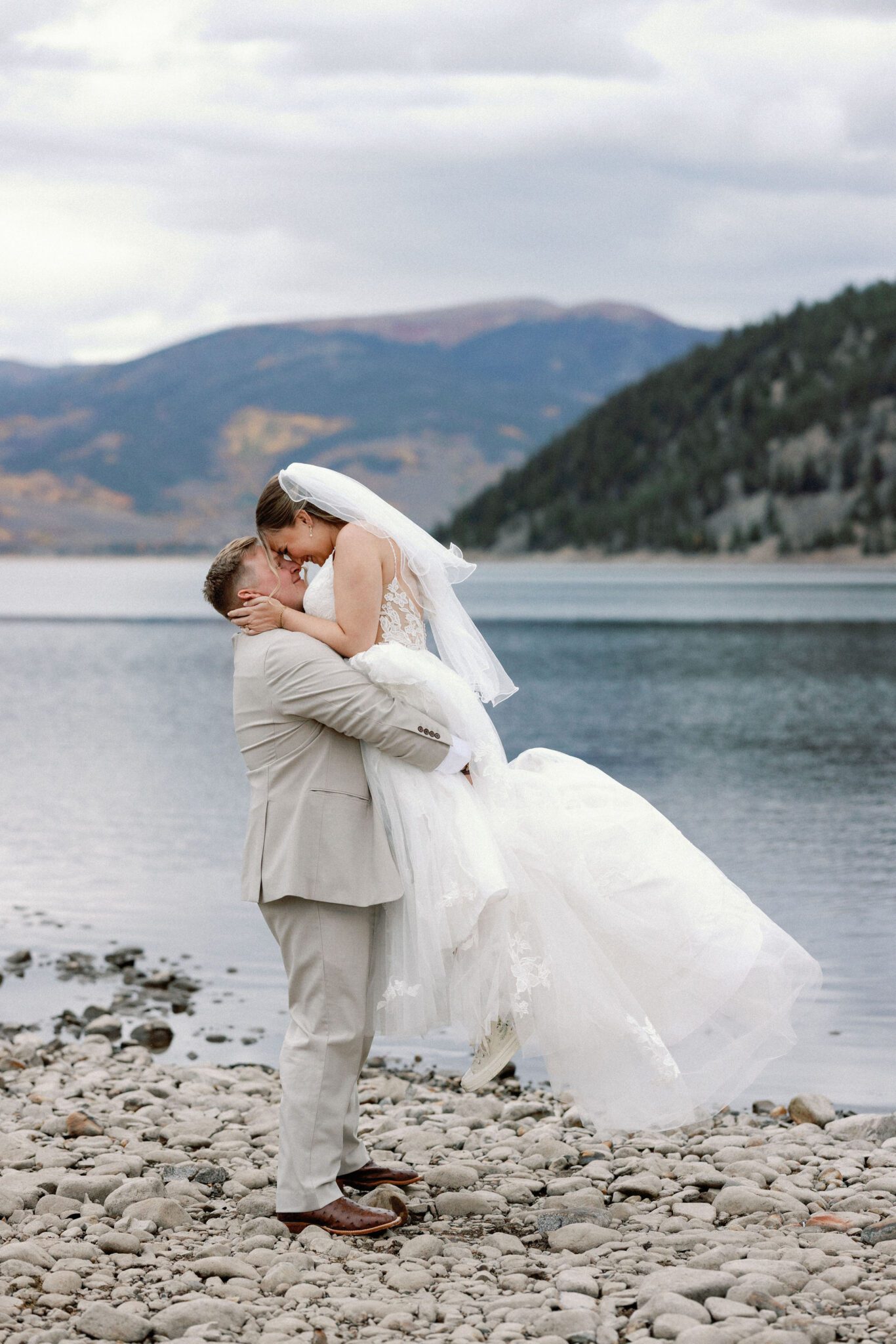 groom lifts up bride during wedding photos at lake dillon, a popular colorado elopement venue