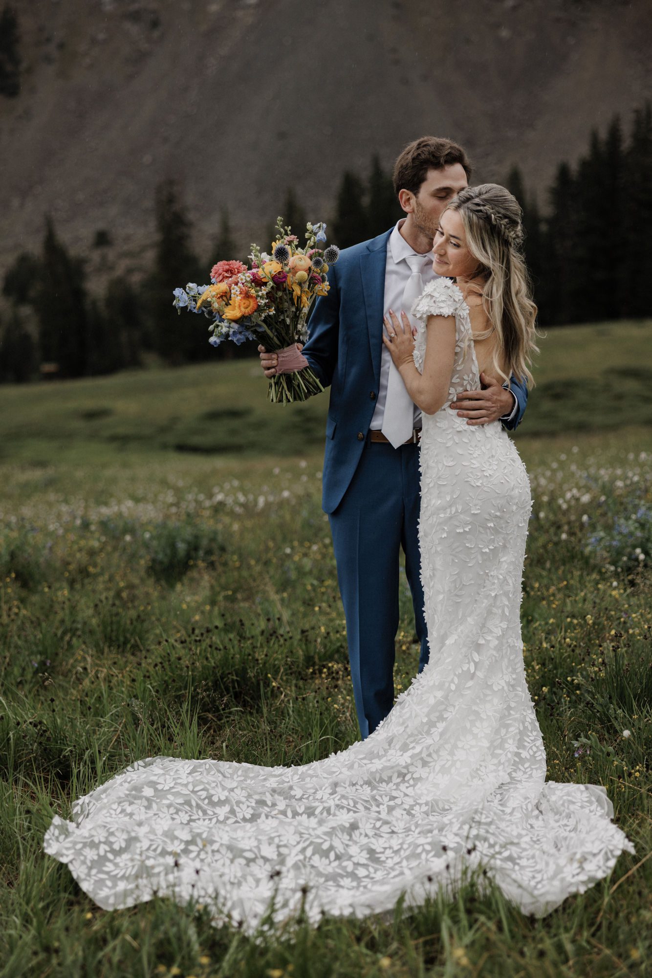 groom hugs bride and kisses her on the cheek during wedding photos