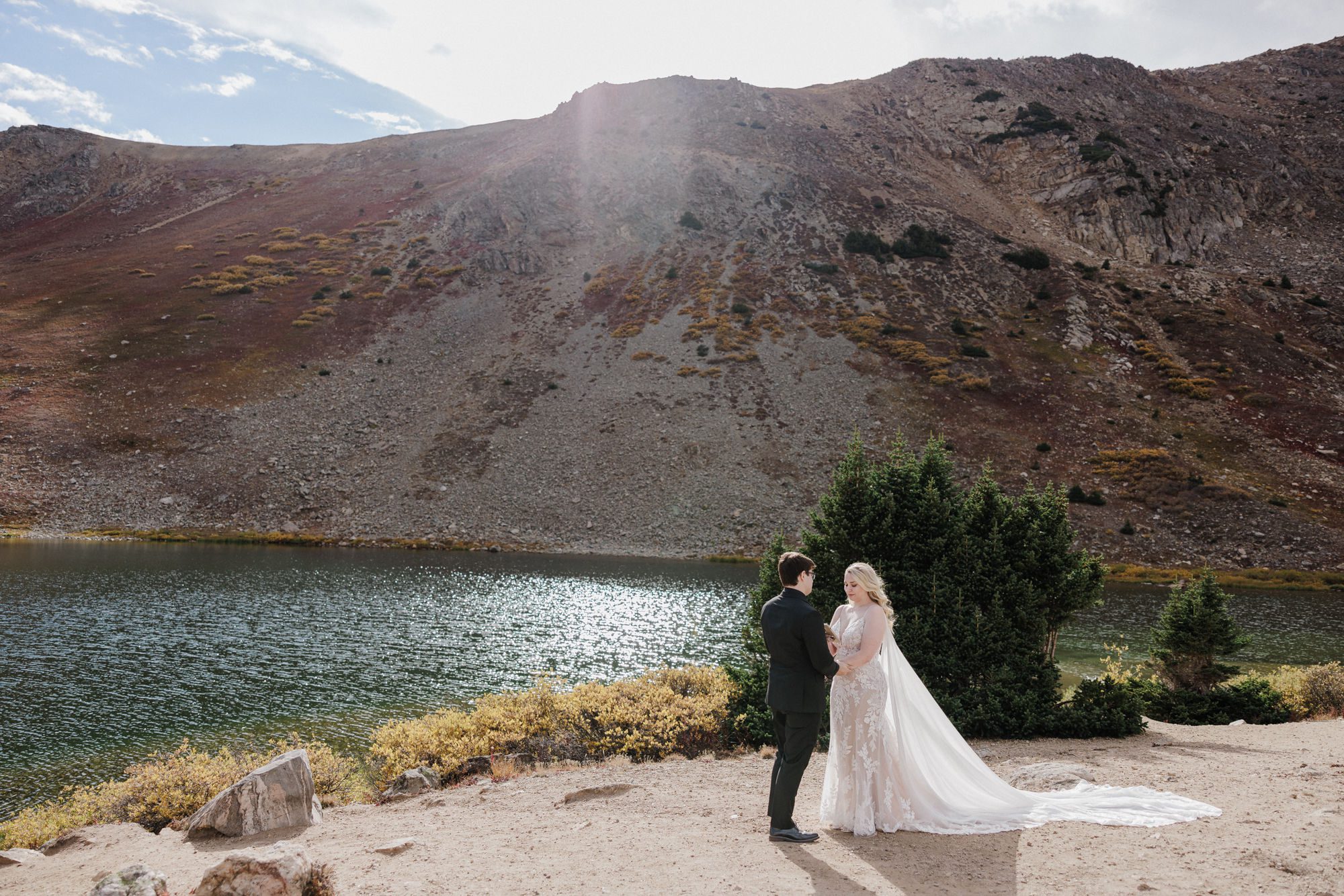 bride and groom stand by alpine lake during colorado micro wedding