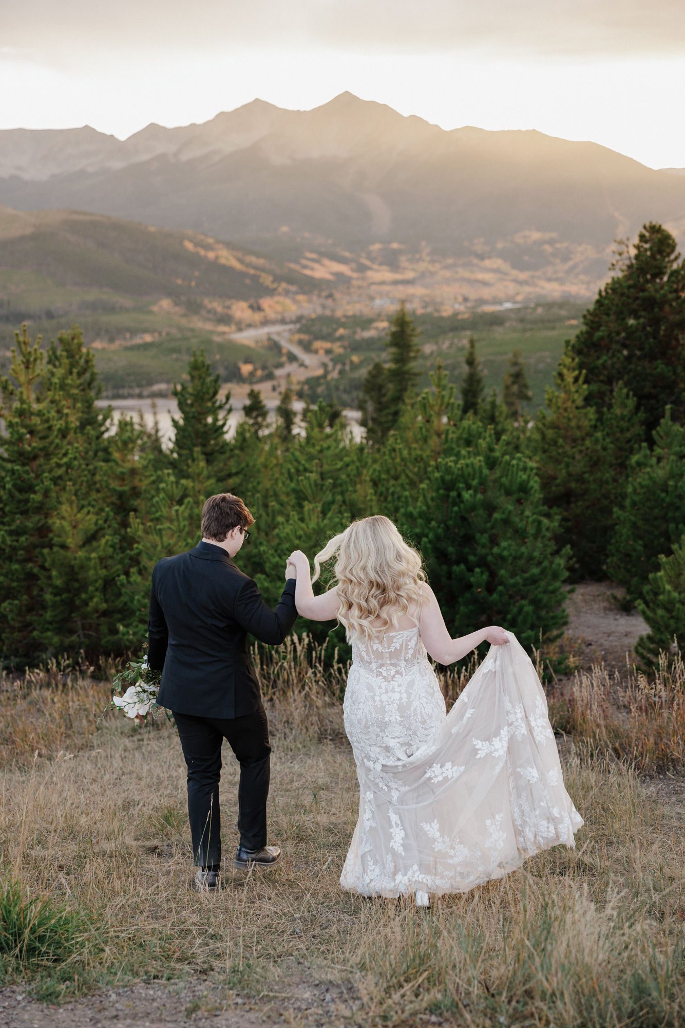bride and groom hold hands and walk down hill during wedding photos