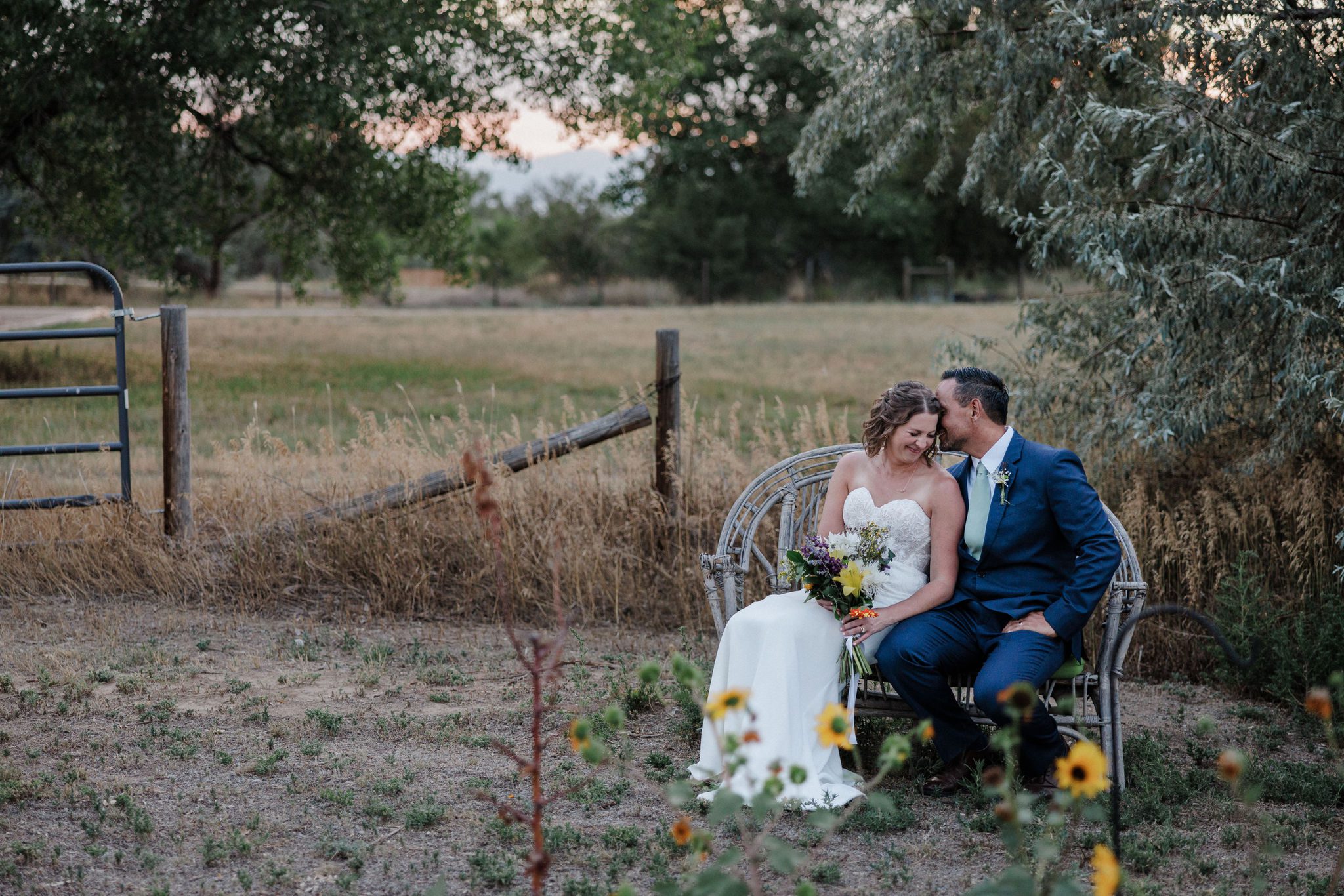 bride and groom sit on chair during sunset wedding photos