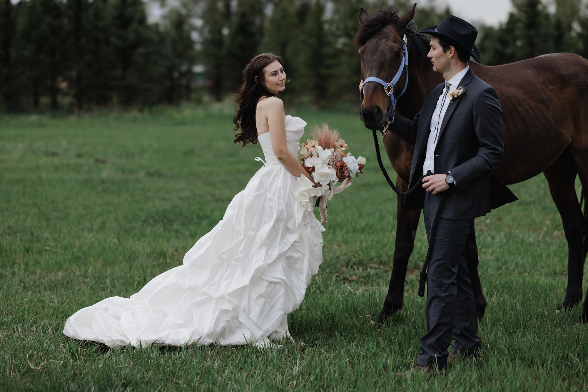 bride and groom walk horse while holding flowers from elopement vendor in colorado