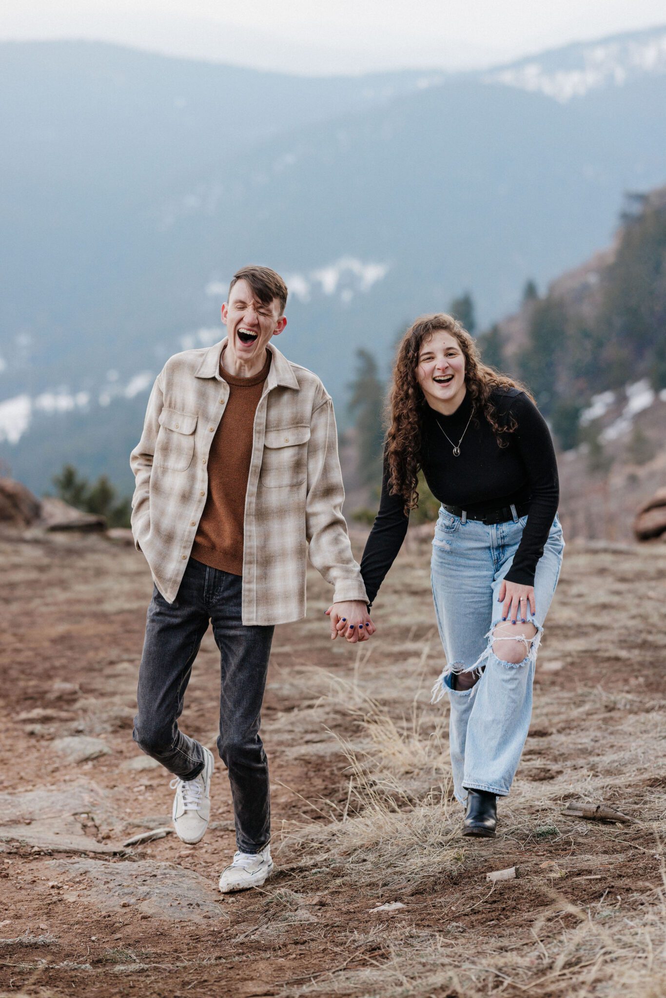 engaged couples smiles and holds hands after choosing the best place to propose in colorado