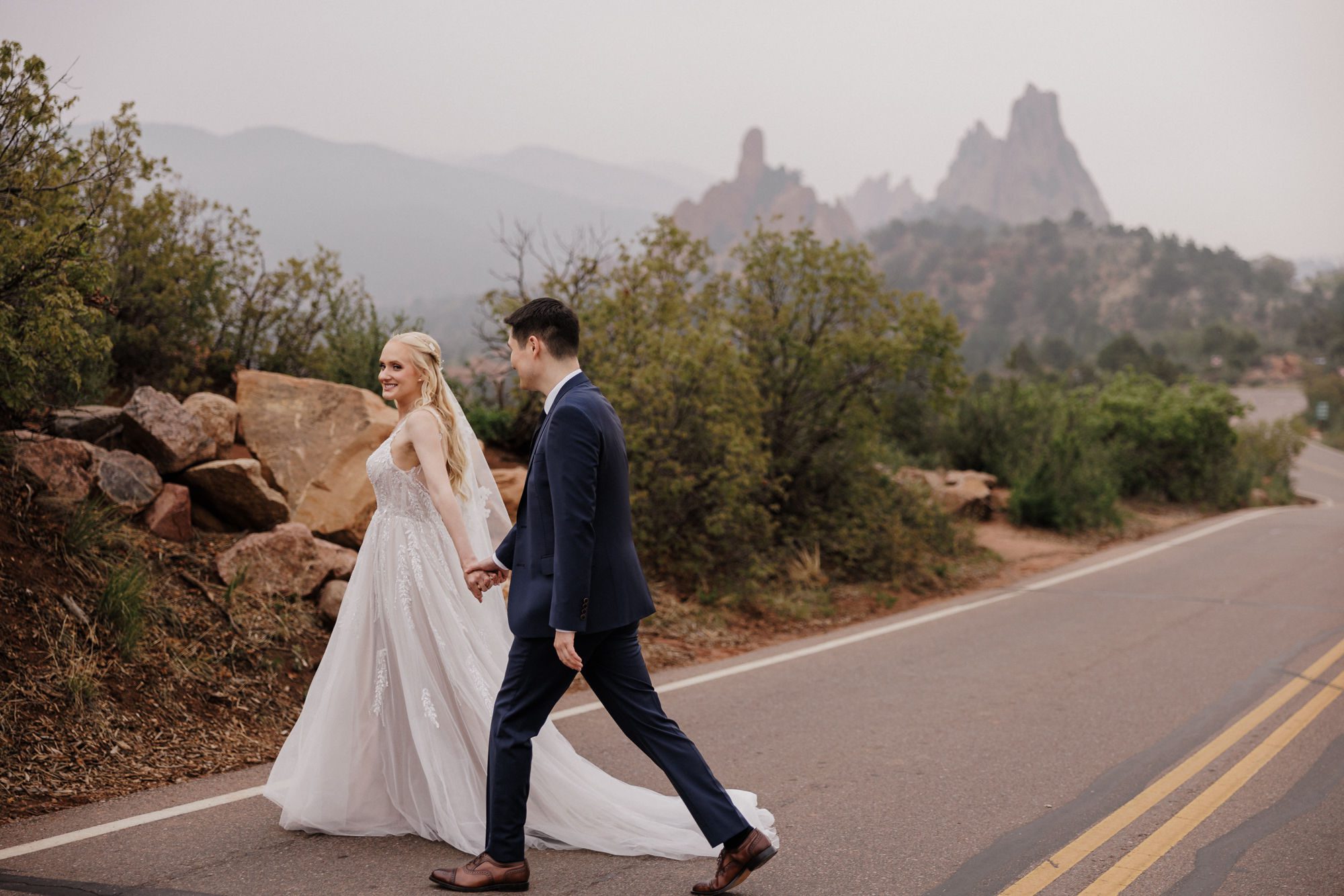bride and groom walk across road at popular colorado proposal location