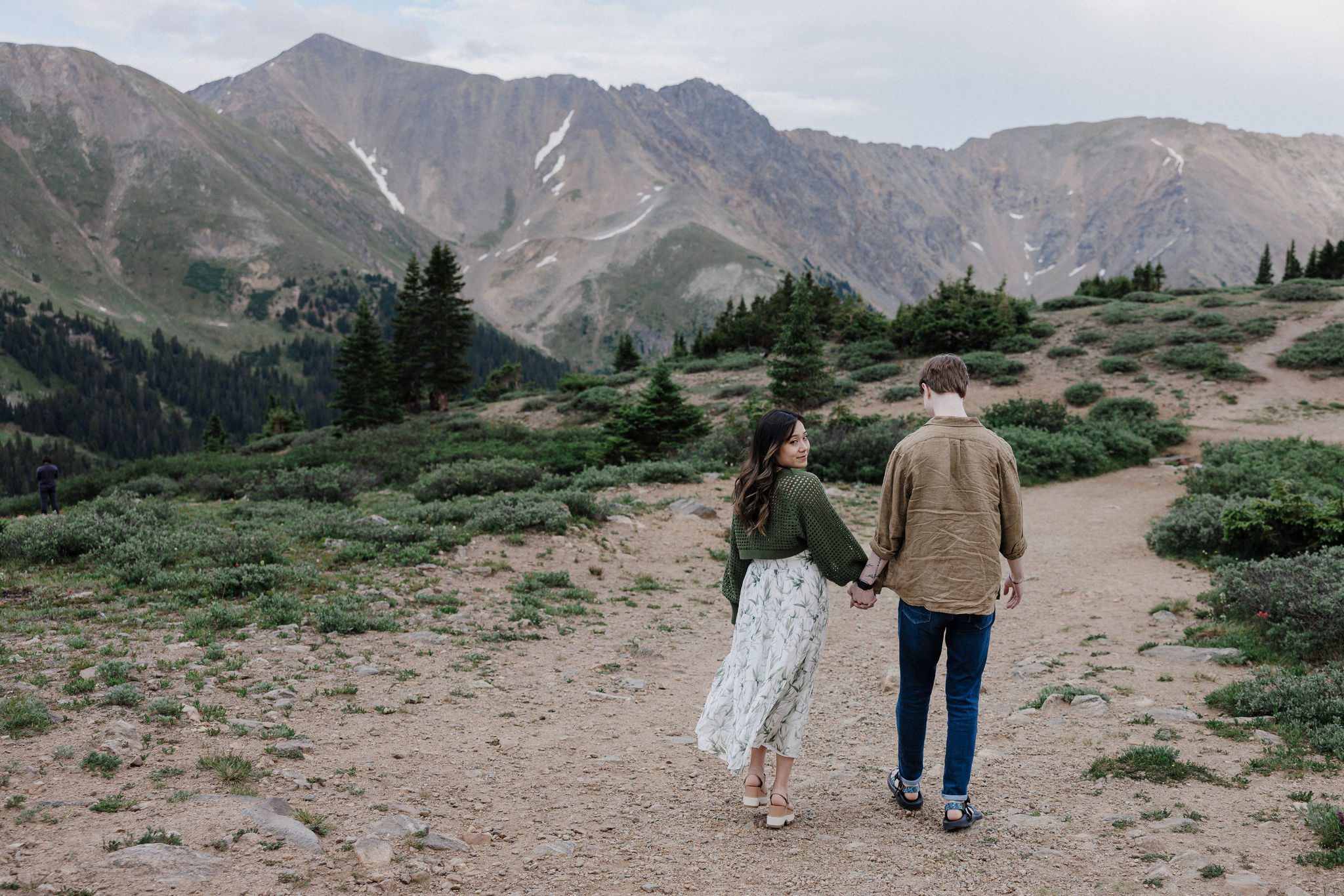 best place to propose in colorado: engaged couple walks on trail in front of breckenridge mountains