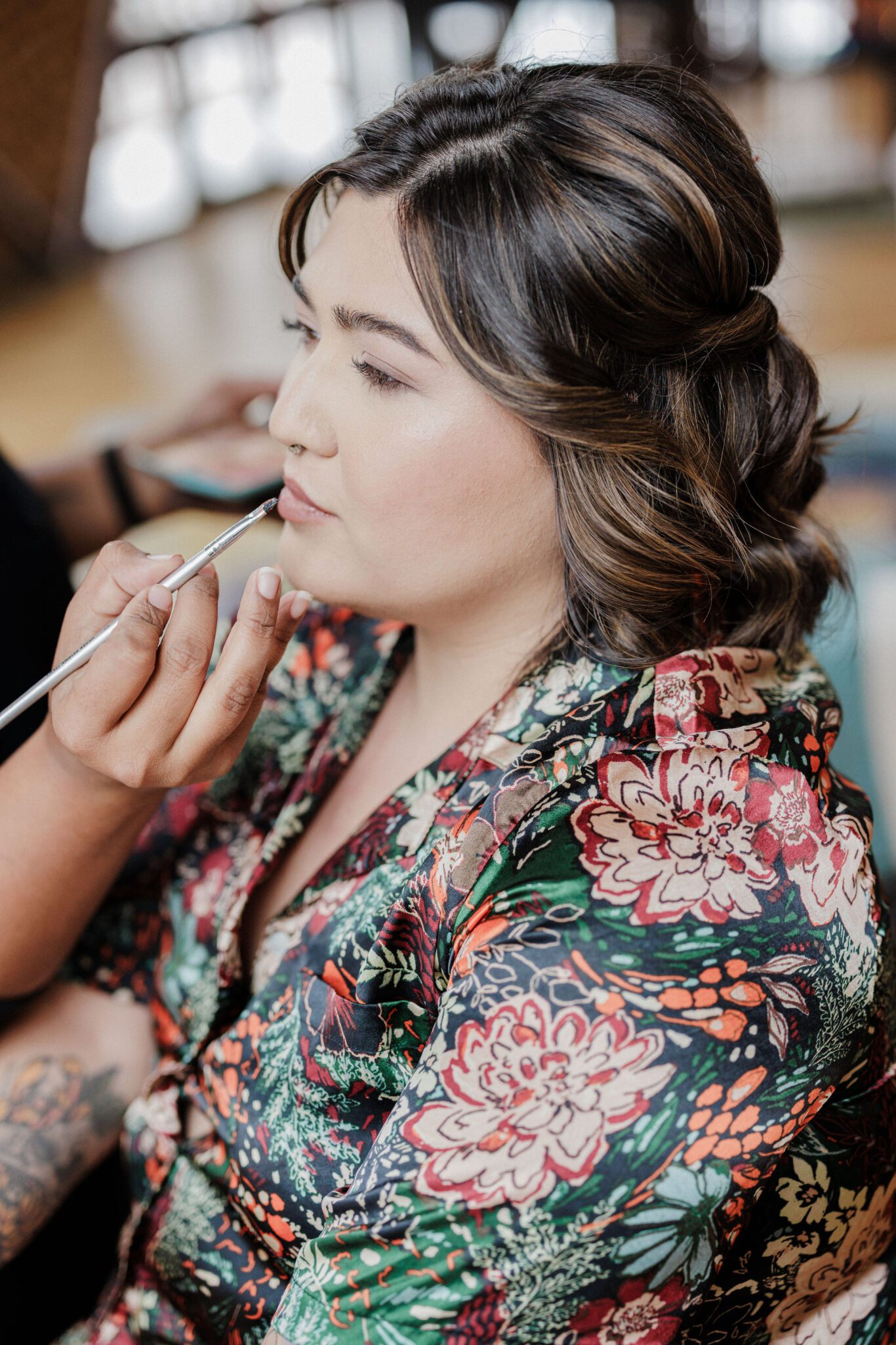 elopement planning: bride sits as hair and makeup artist does her lips for her wedding day