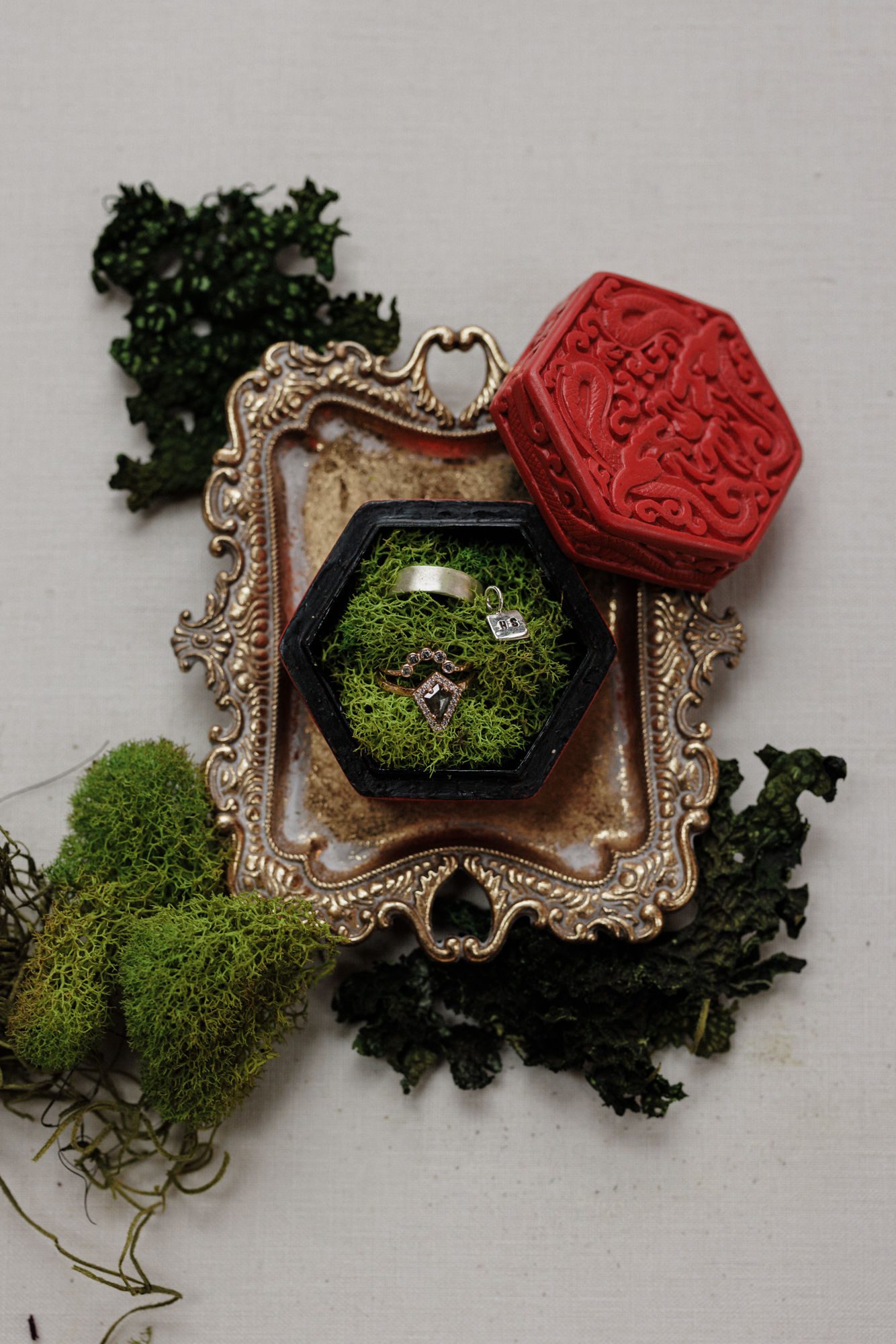 elopement planning: wedding rings sit in red chinese ring box with moss