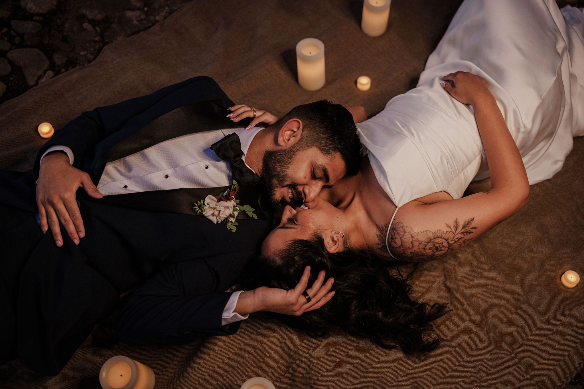 elopement planning: bride and groom lay on blanket surrounded by little candles