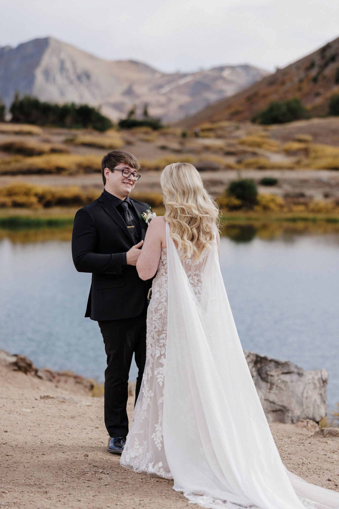 bride and groom smile at each other after their first look in the mountains
