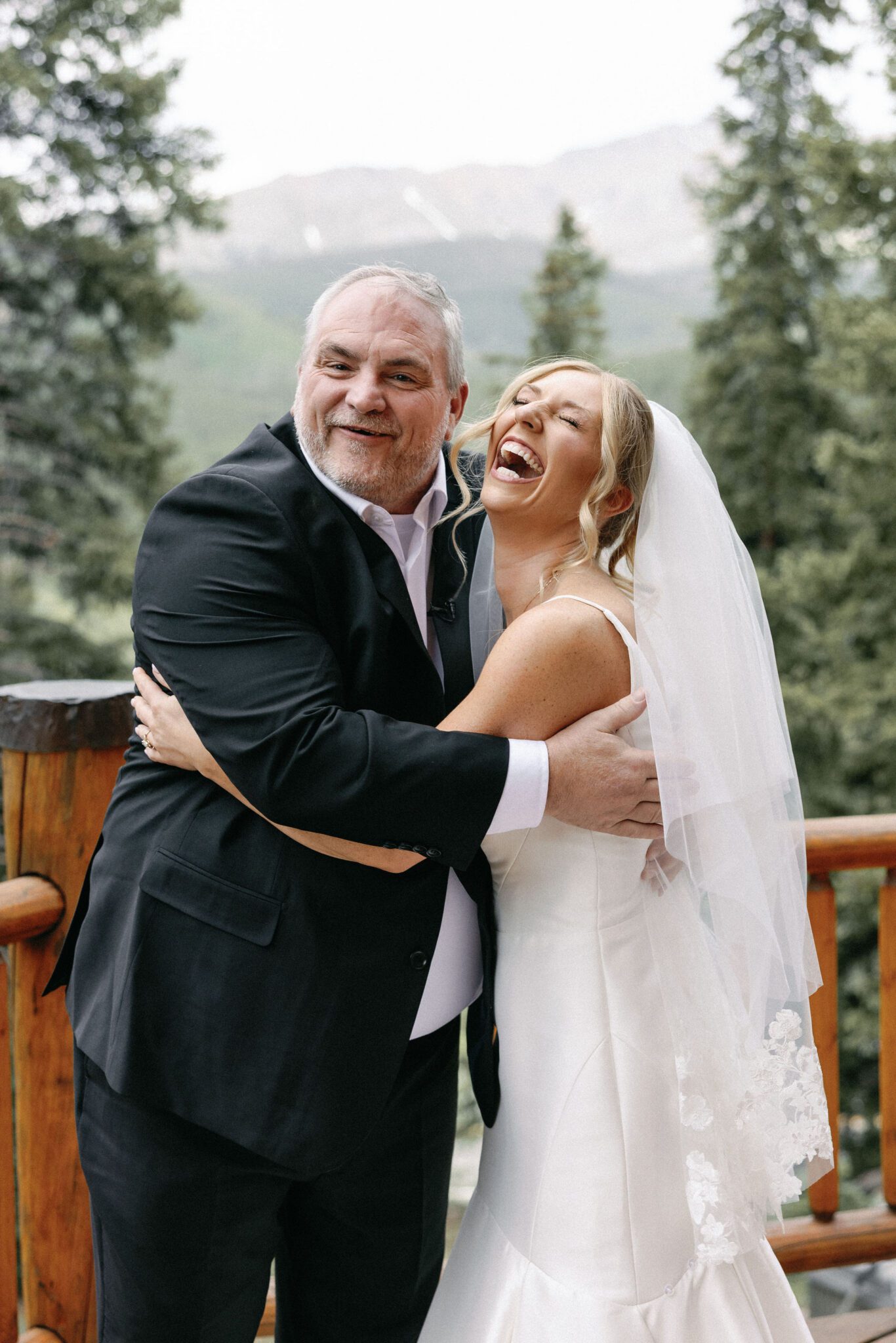 bride and father hug and laugh as they take photos before the wedding ceremony