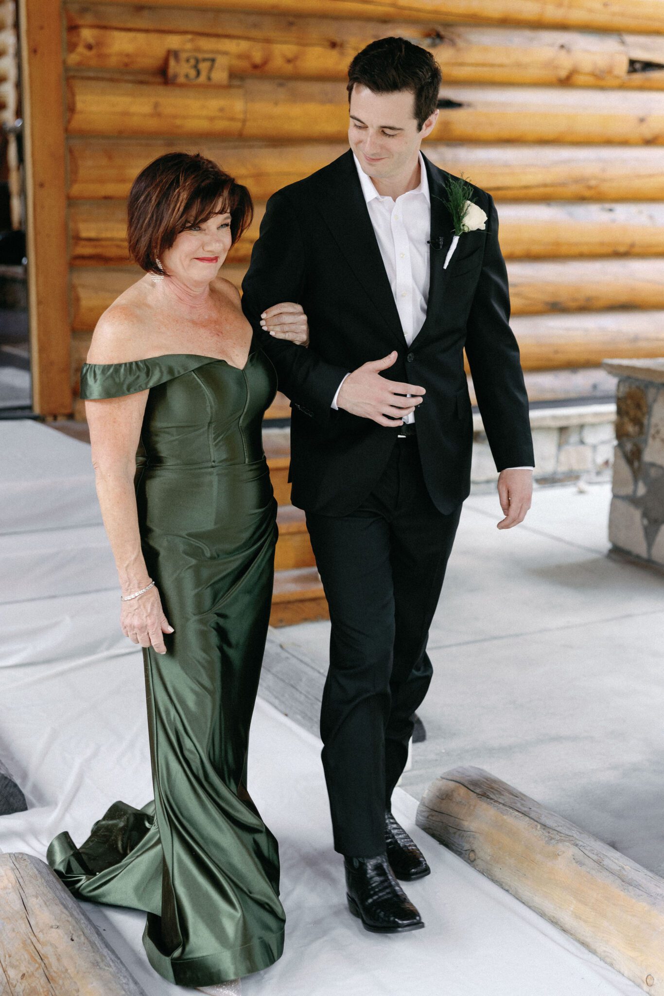 groom walks down the aisle with his mother