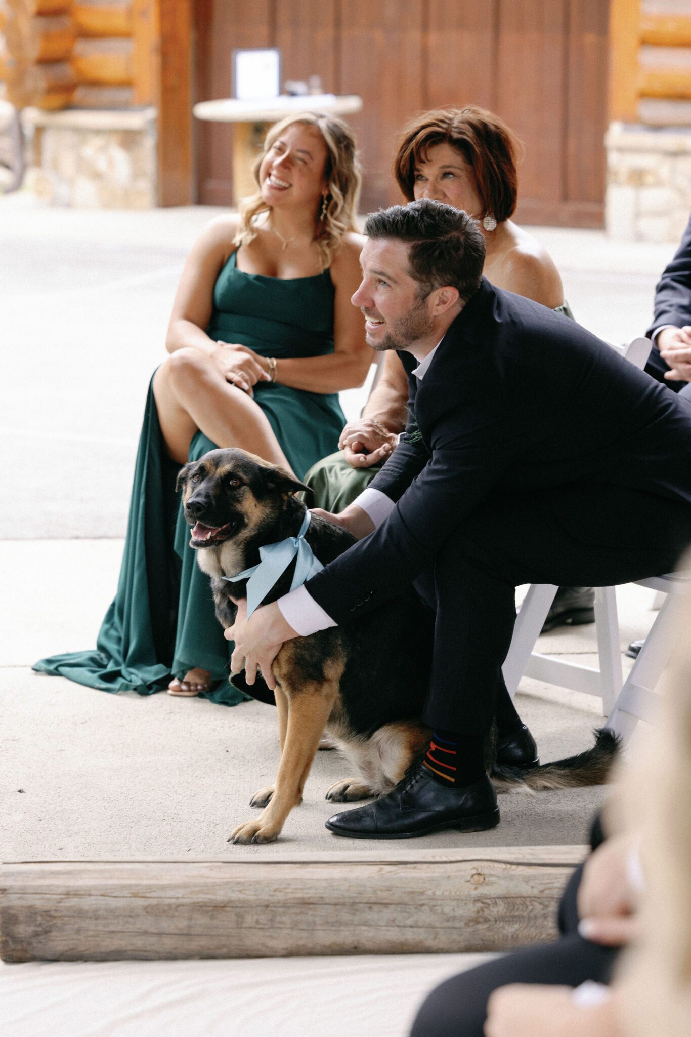 one of the groomsmen holds their dog during the wedding ceremony