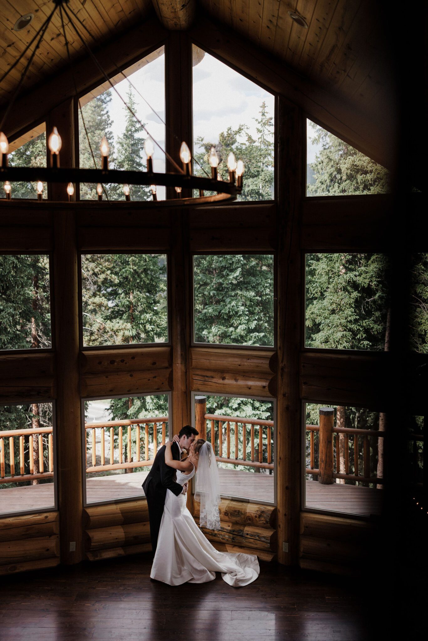 bride and groom kiss in front of the large floor to ceiling windows at the colorado airbnb during wedding