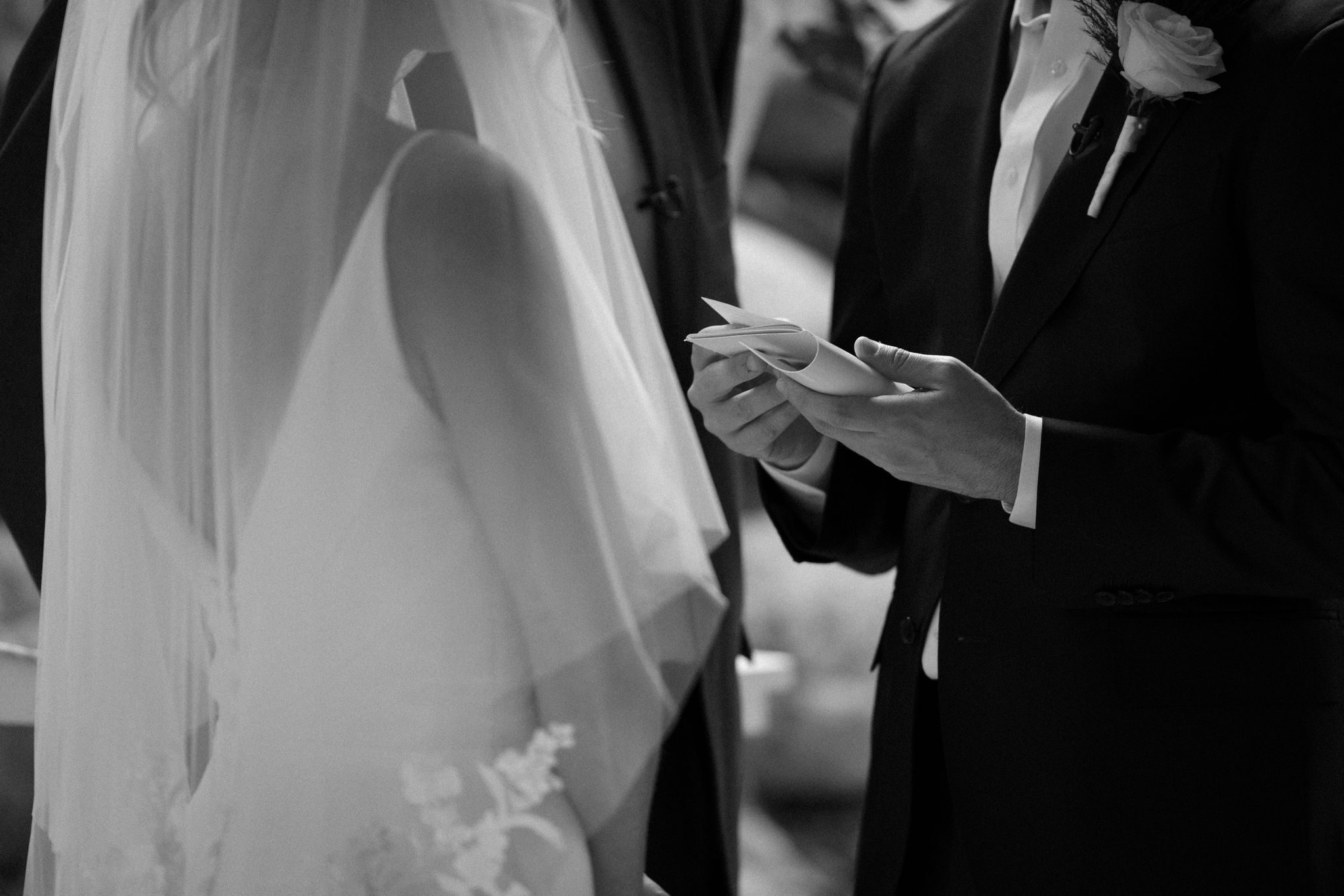 close up image of groom holding his vow book as he reads