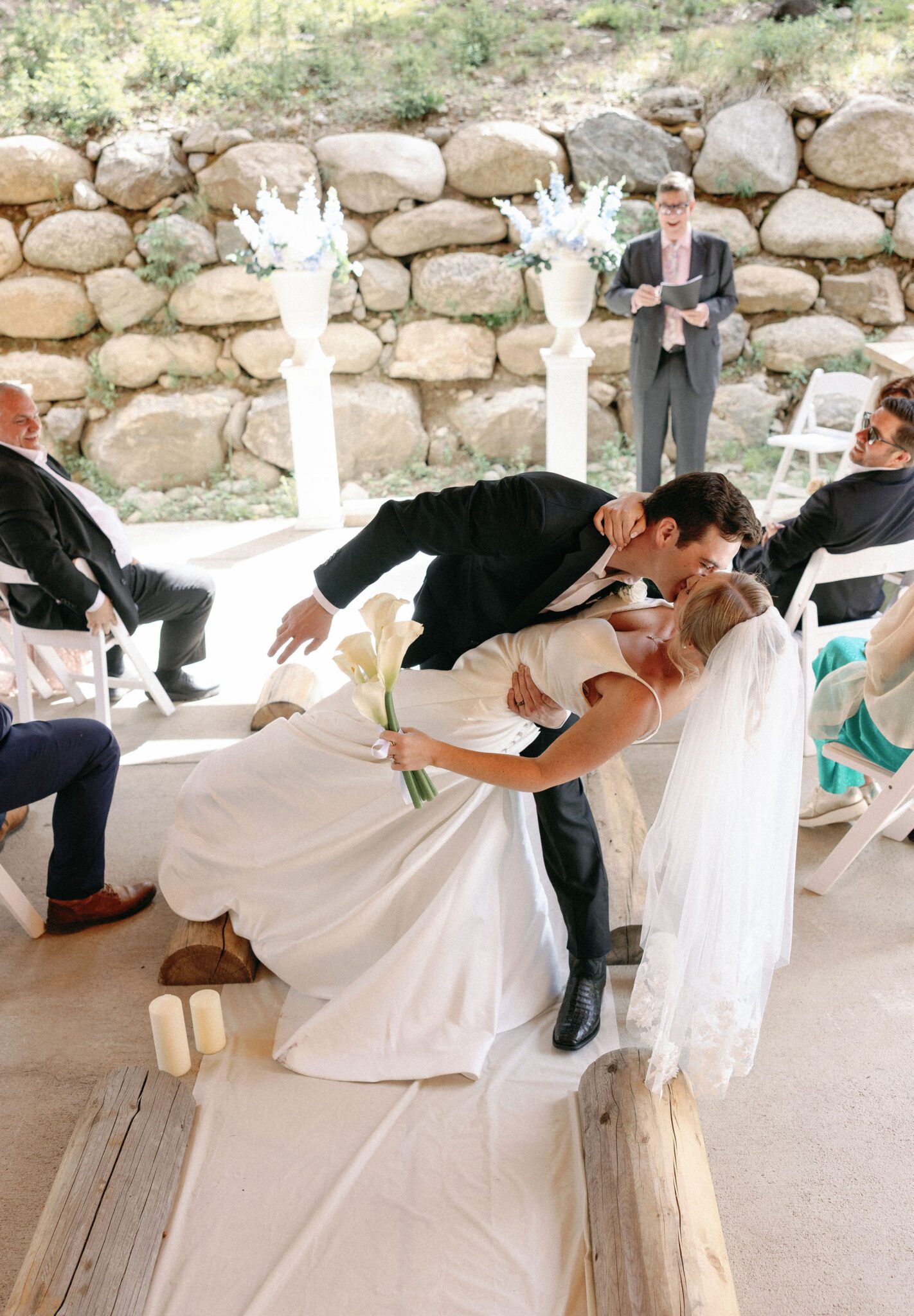 bride and groom stop mid-aisle to share a kiss at the end of their airbnb wedding ceremony