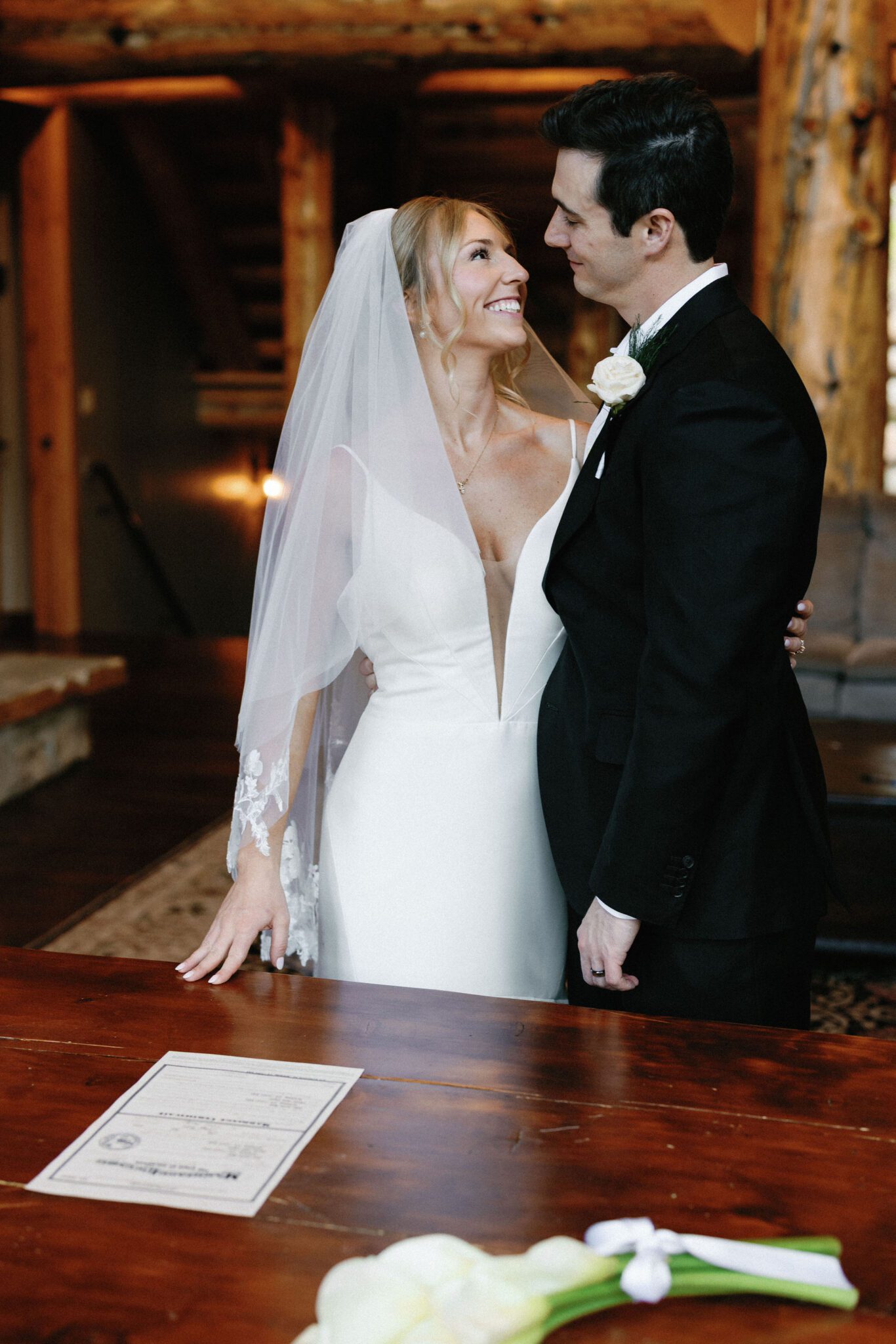 bride and groom hug and smile at each other while signing their colorado marriage license in the airbnb