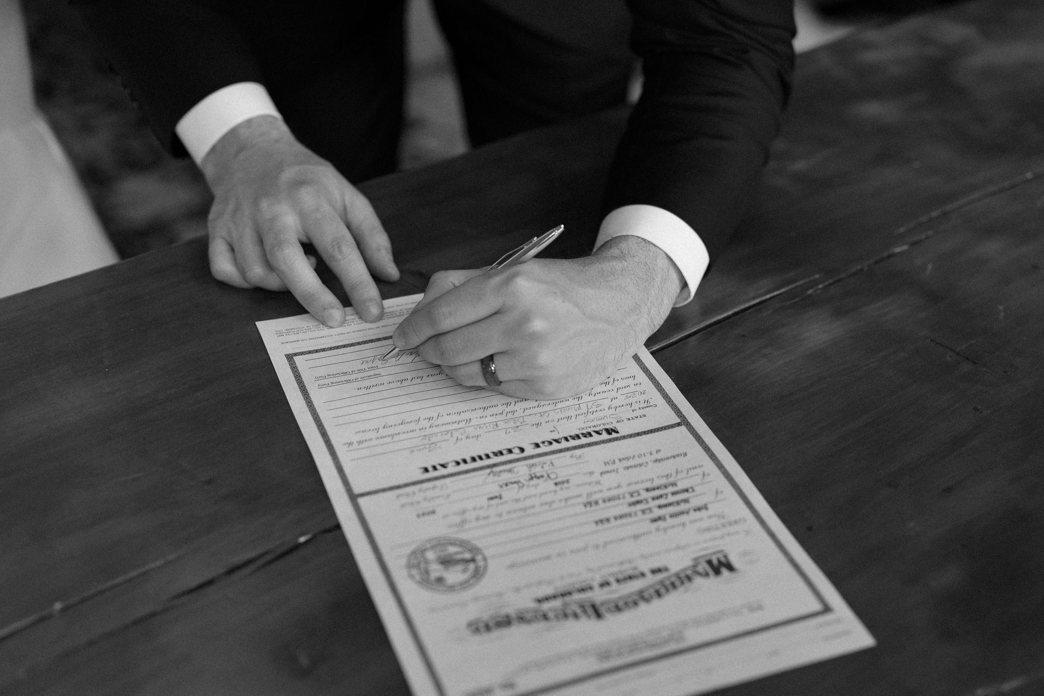 close up image of the groom signing the marriage license