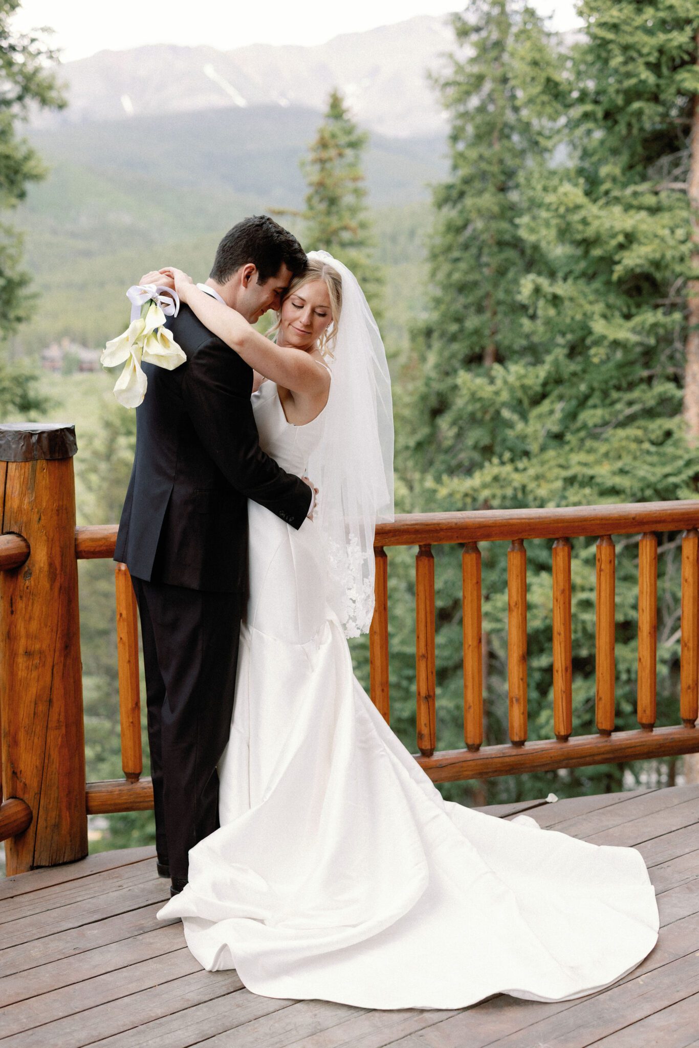 bride and groom take wedding photos onthe deck of the airbnb overlooking the colorado mountains