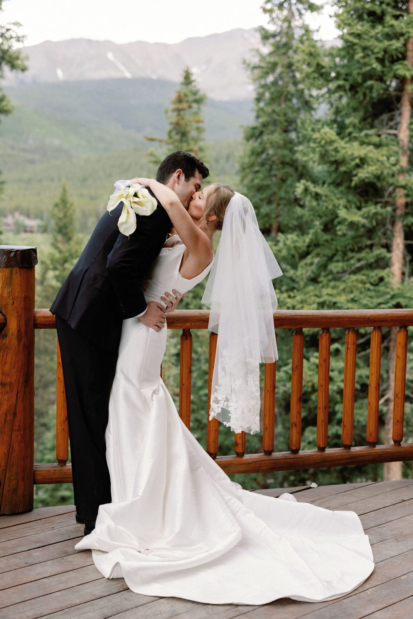 bride and groom kiss and take wedding photos onthe deck of the airbnb overlooking the colorado mountains