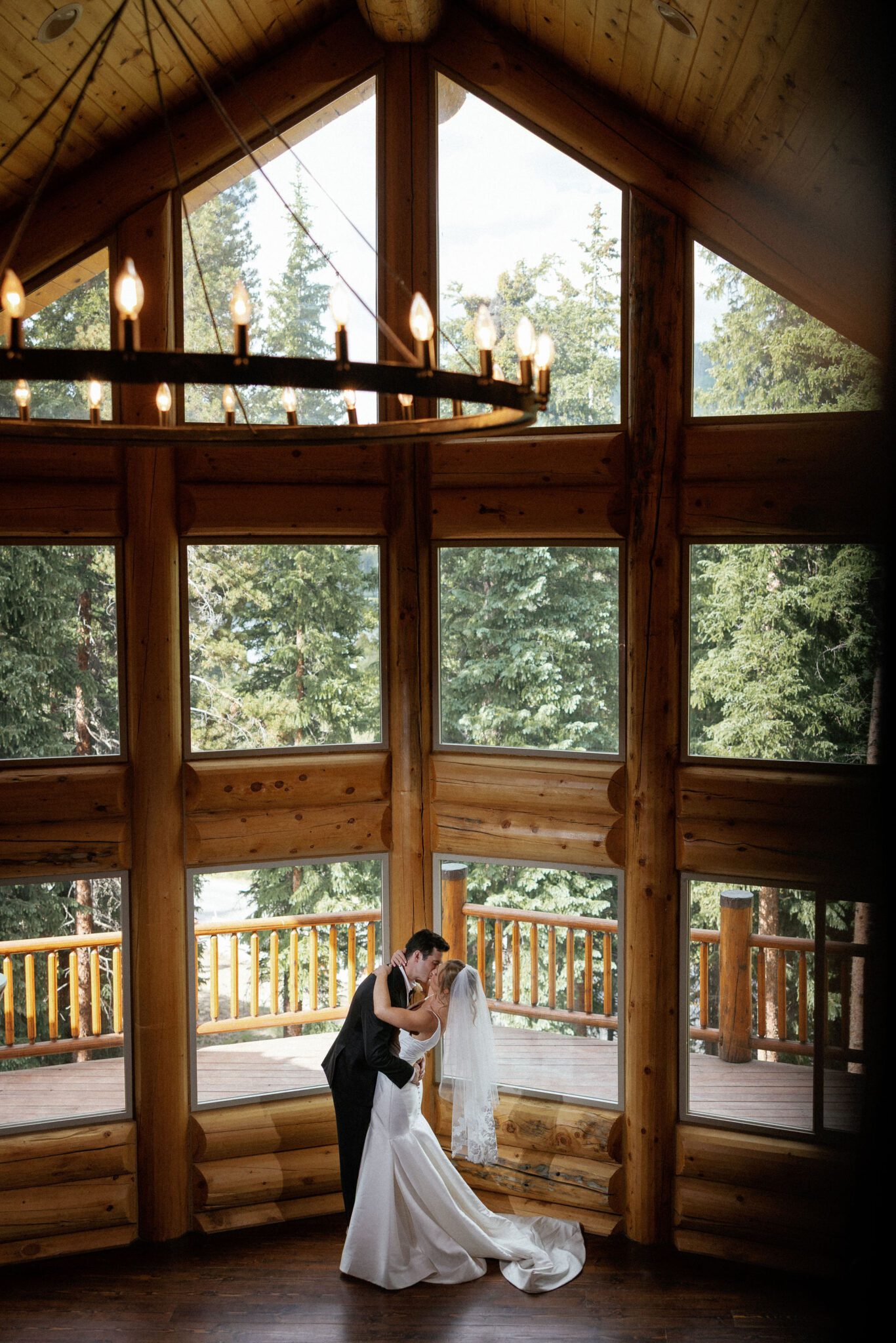 bride and groom kiss in front of the large floor-to-ceiling window at the airbnb during wedding