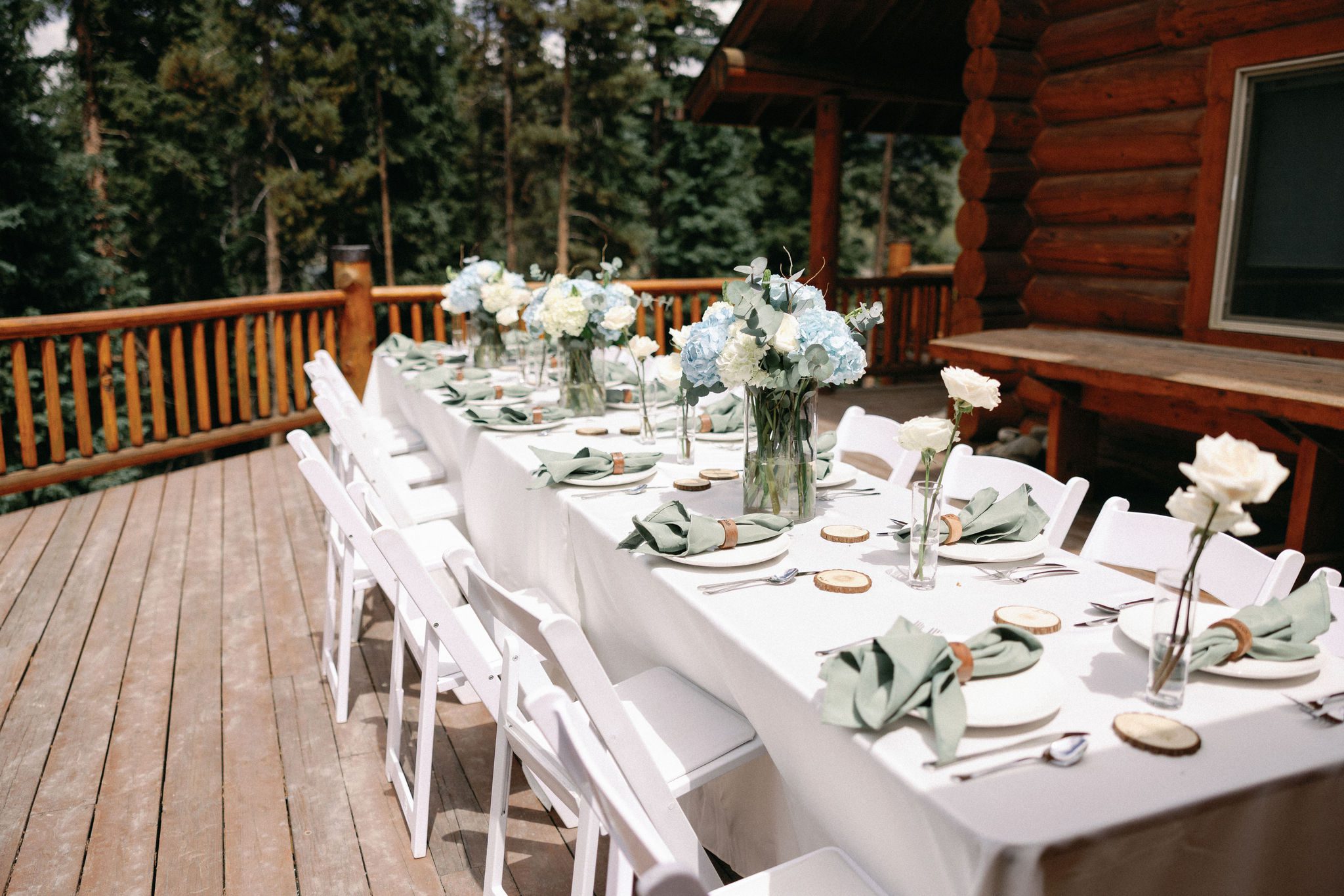a table on the deck of an airbnb is set up for a wedding reception