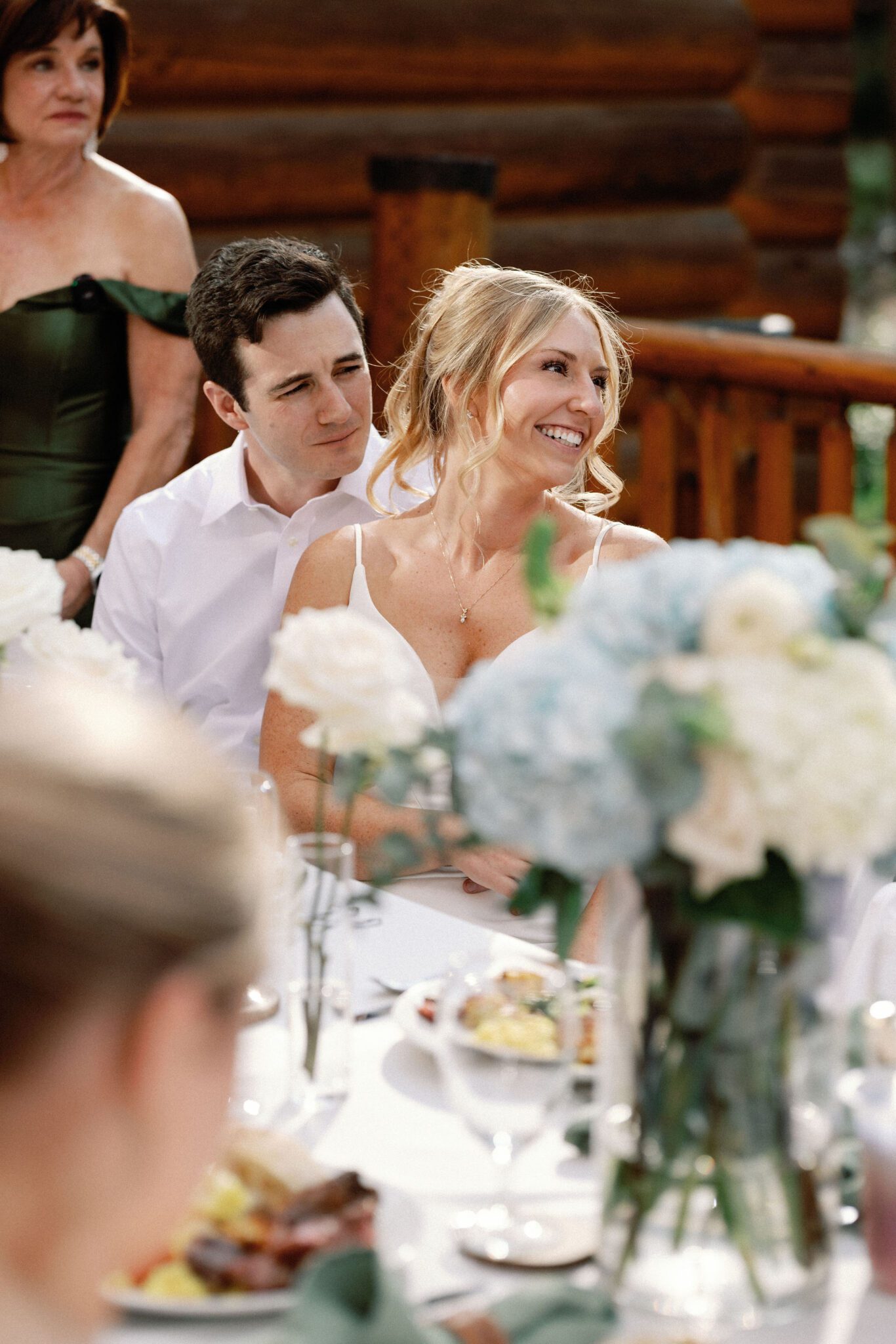 bride and groom smile as they listen to their guests give wedding toasts
