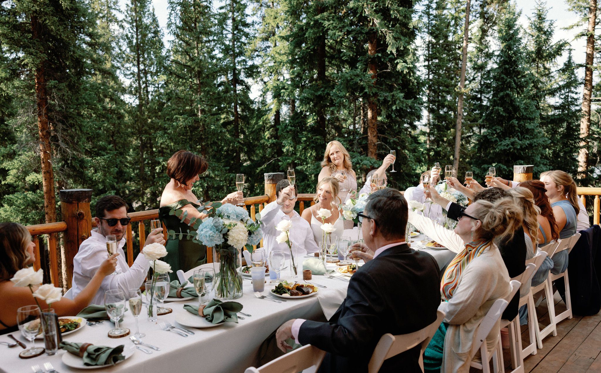 wedding guests raise their champagne glasses to toast during the wedding reception on the deck of the airbnb