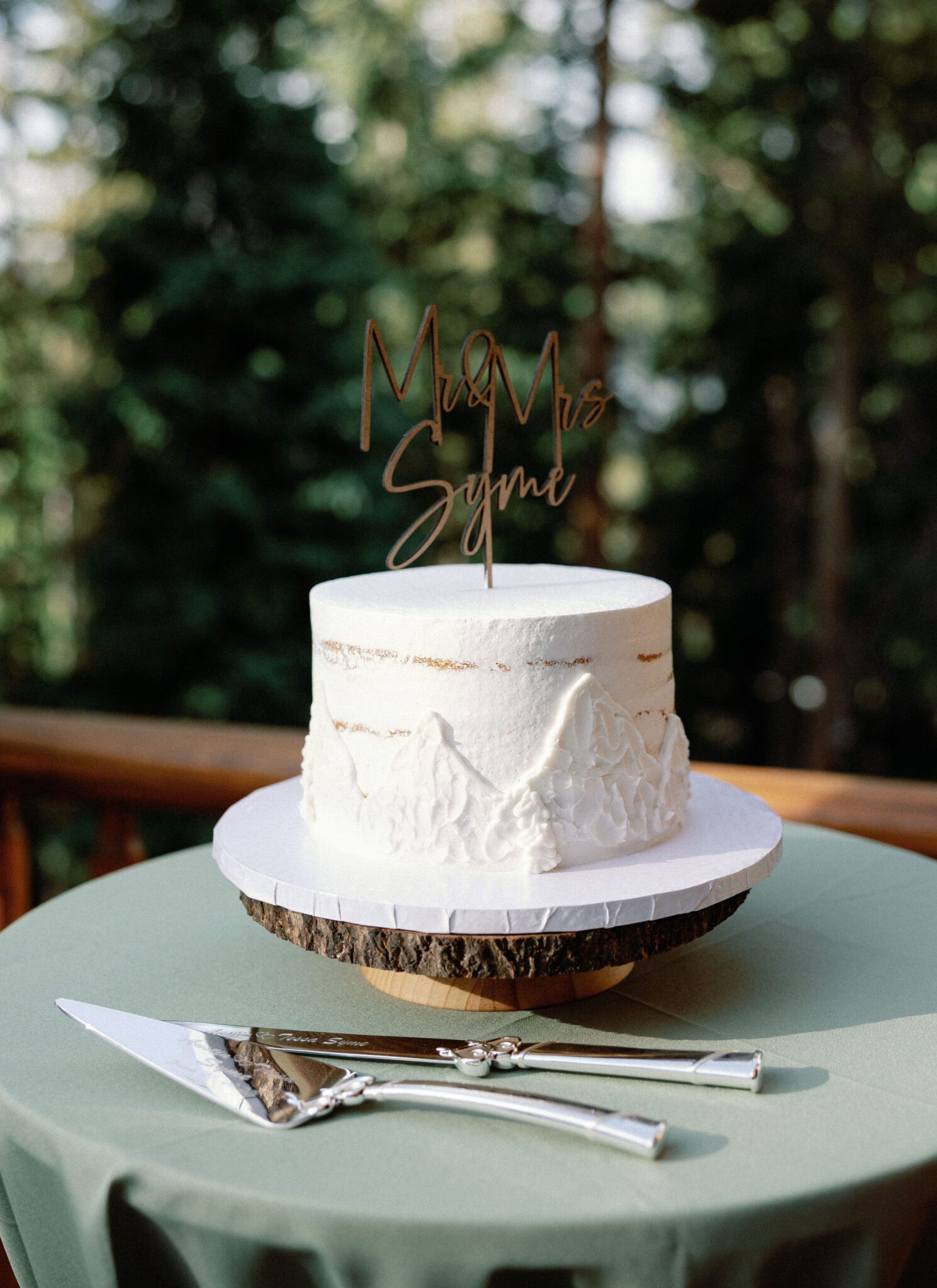white wedding cake with mountains on the sides and a 'mr&mrs' sign on top