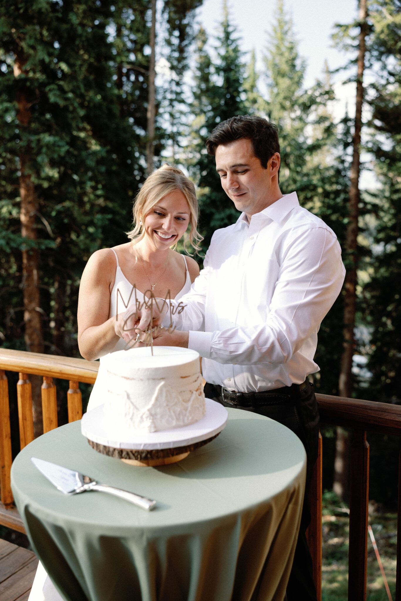 bride and groom both cut into wedding cake during reception on the deck of the airbnb