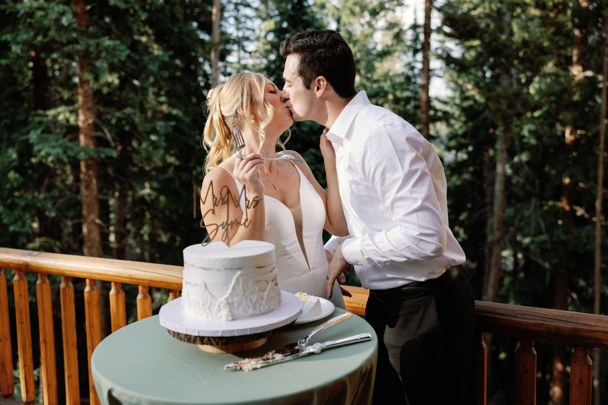 bride and groom kiss after they cut their wedding cake and eat a bite