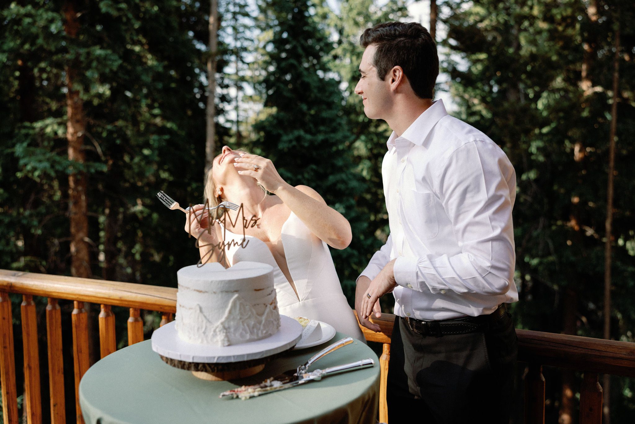 bride and groom laugh after they each eat a bite of their wedding cake