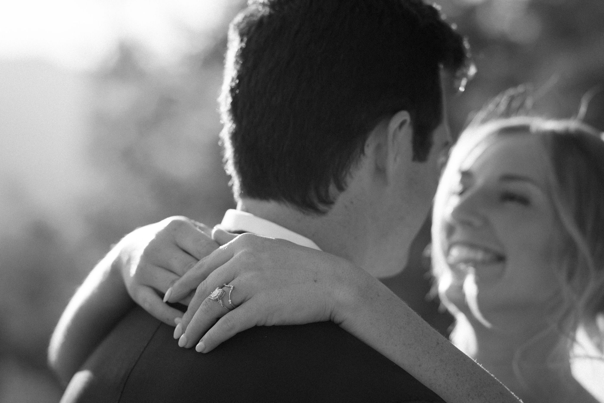 bride puts arms around grooms neck and smiles up at him