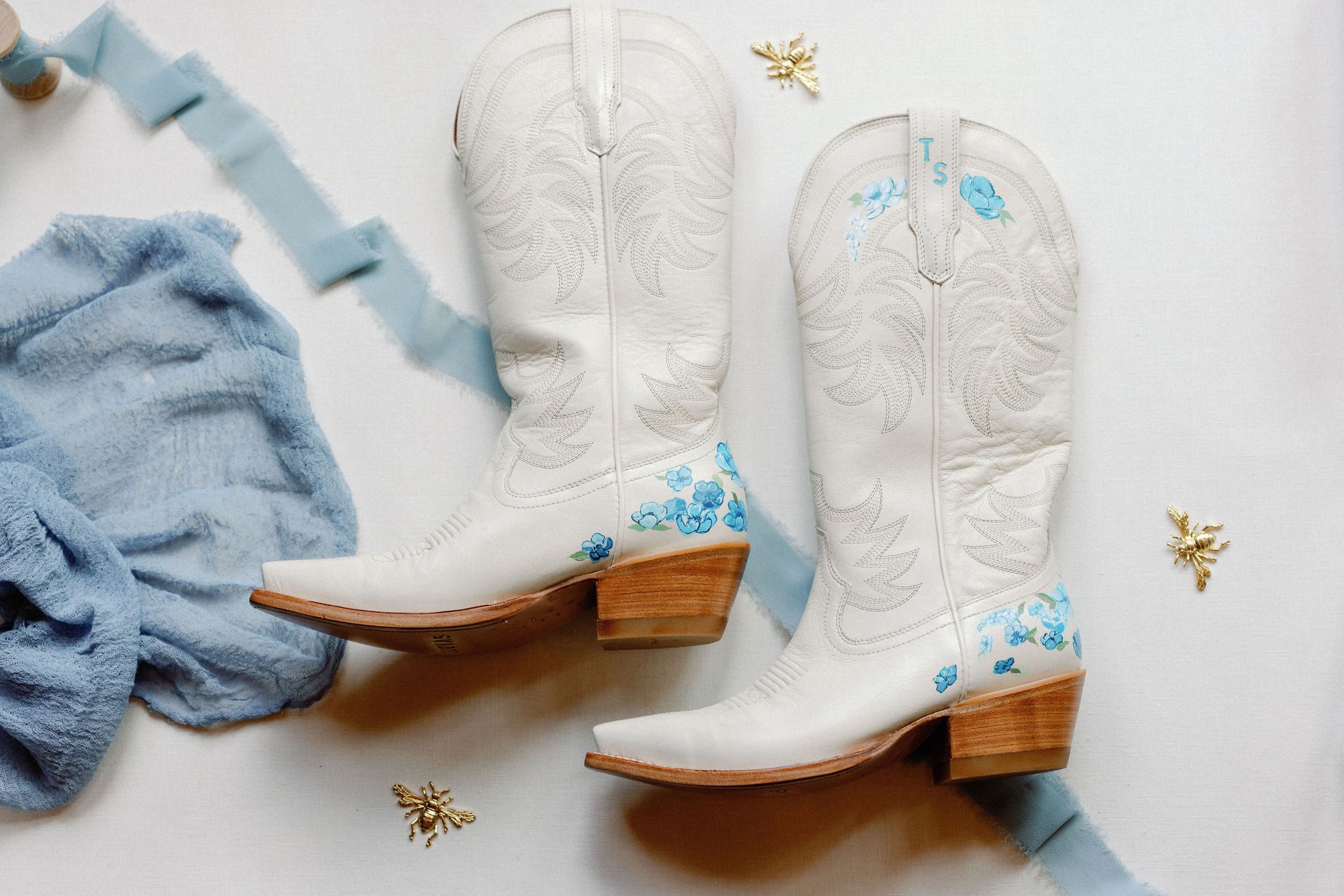flat lay photo of white cowboy boots with turquoise details for a wedding