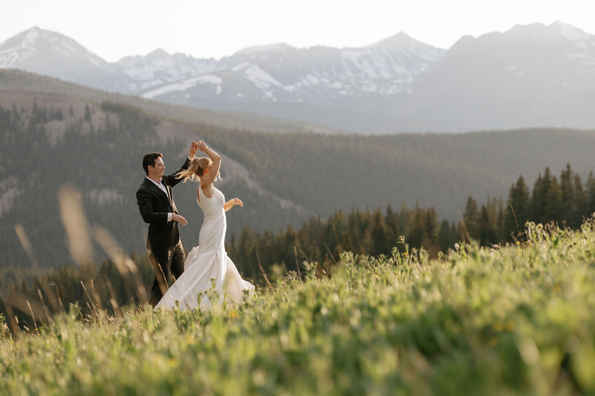 after colorado airbnb wedding, groom twirls bride while dancing in the mountains during sunset