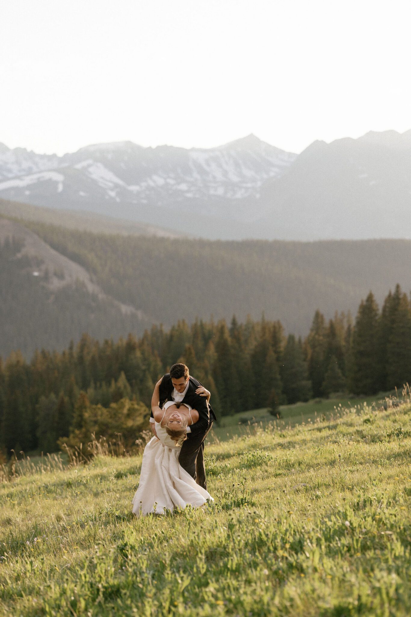 after colorado airbnb wedding, groom dips bride while dancing in the mountains during sunset