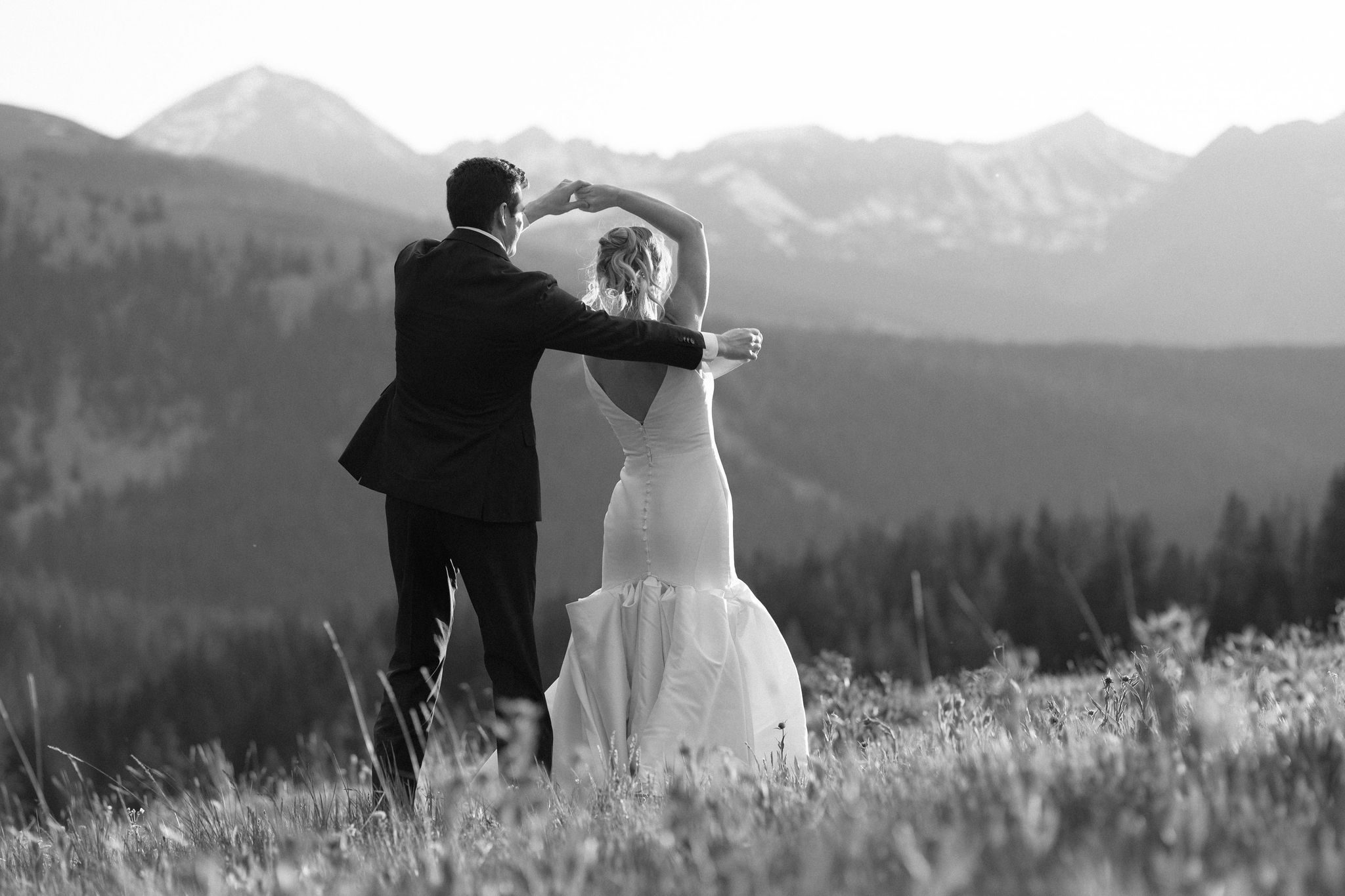 after airbnb wedding, groom twirls bride while dancing in the Colorado mountains during sunset