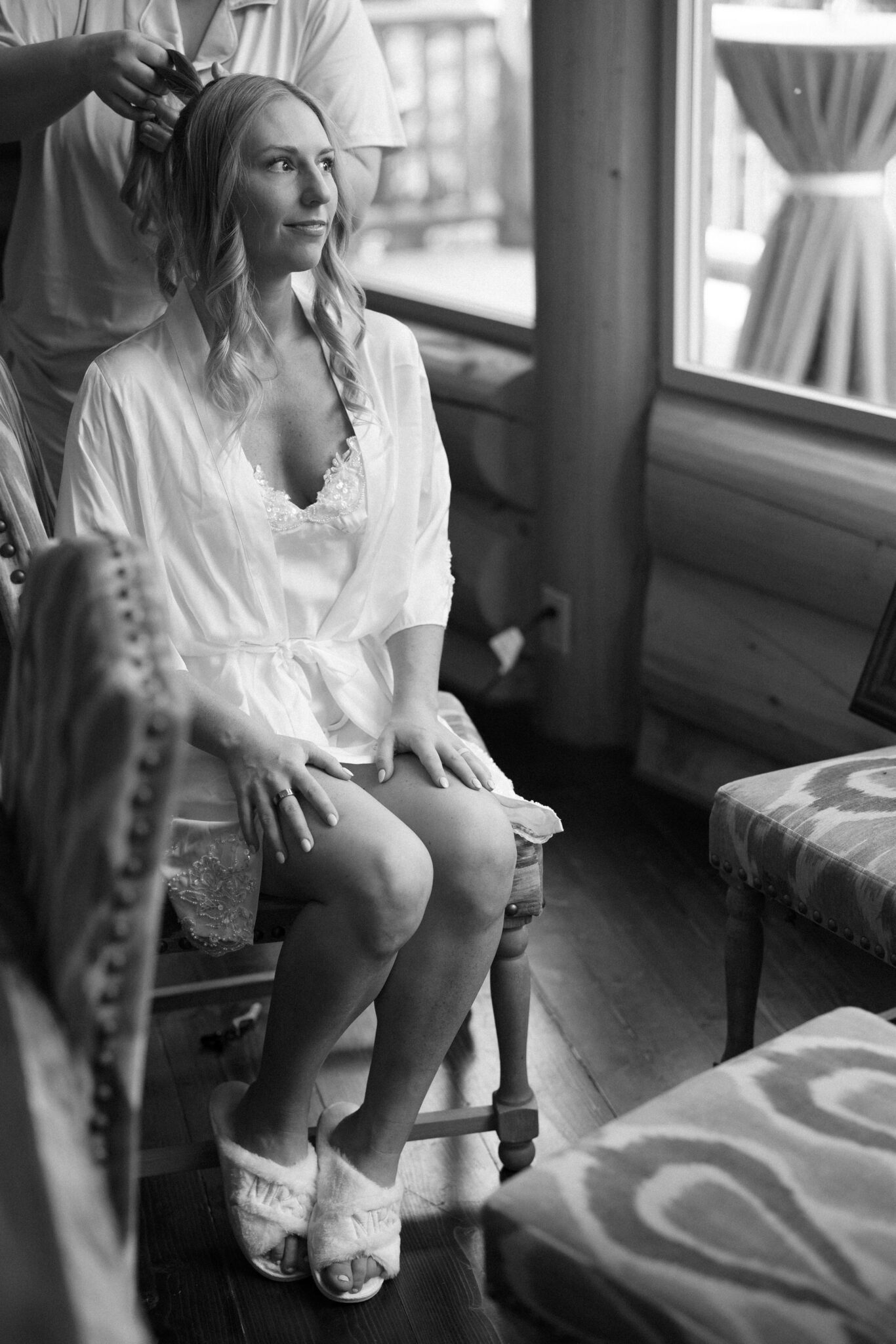 bride gets her hair done for her wedding while looking for the wedding