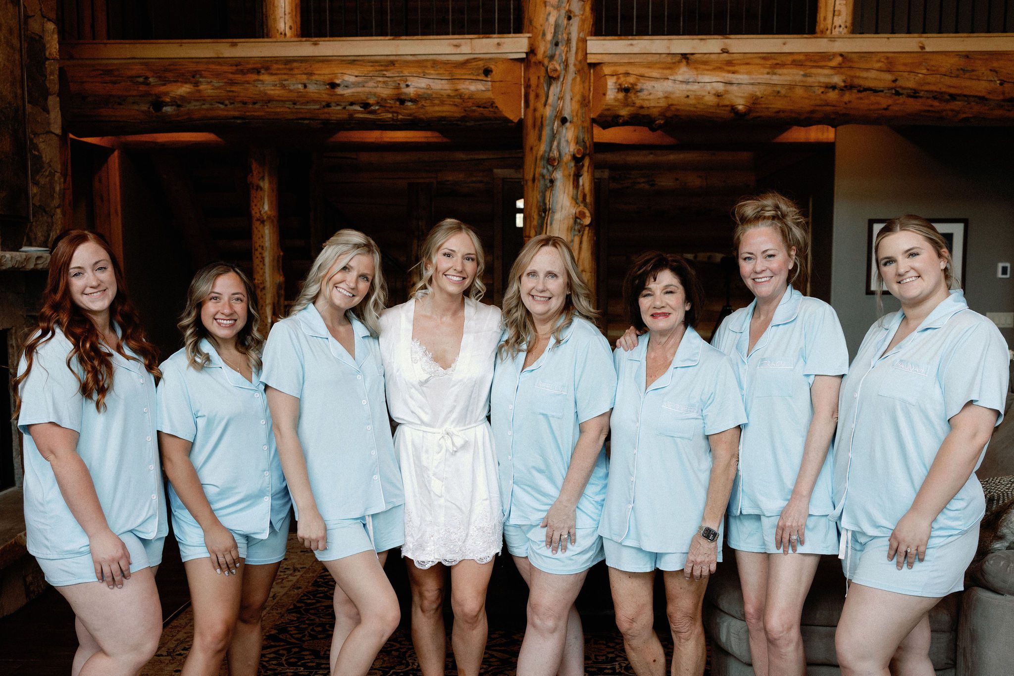 bride stands with her bridesmaids and smile at the photographer during wedding photos in the airbnb